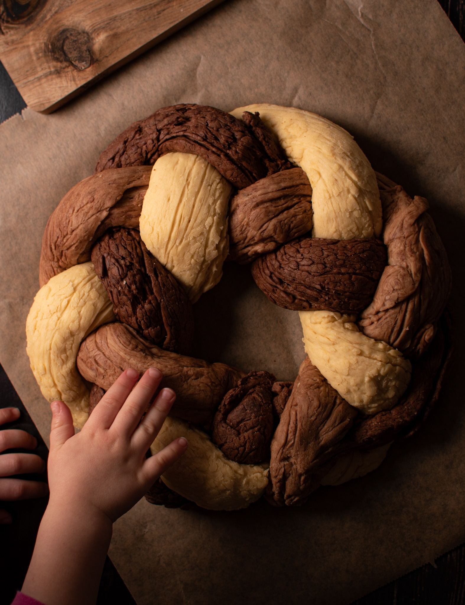 bread wreath with three colours dough, child's hand tapping it