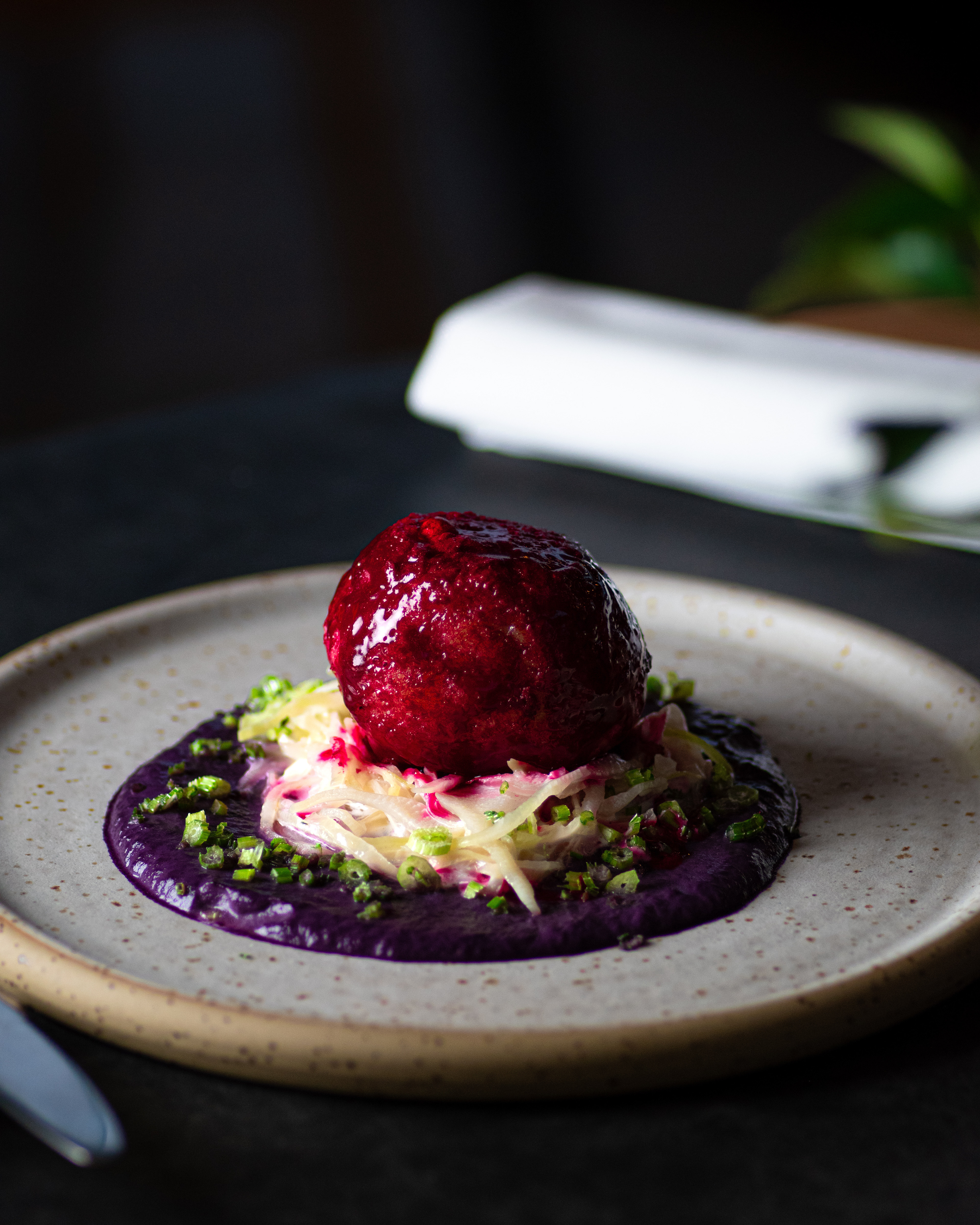 beetroot dumpling with cream of red cabbage on white plate on black background in the restaurant