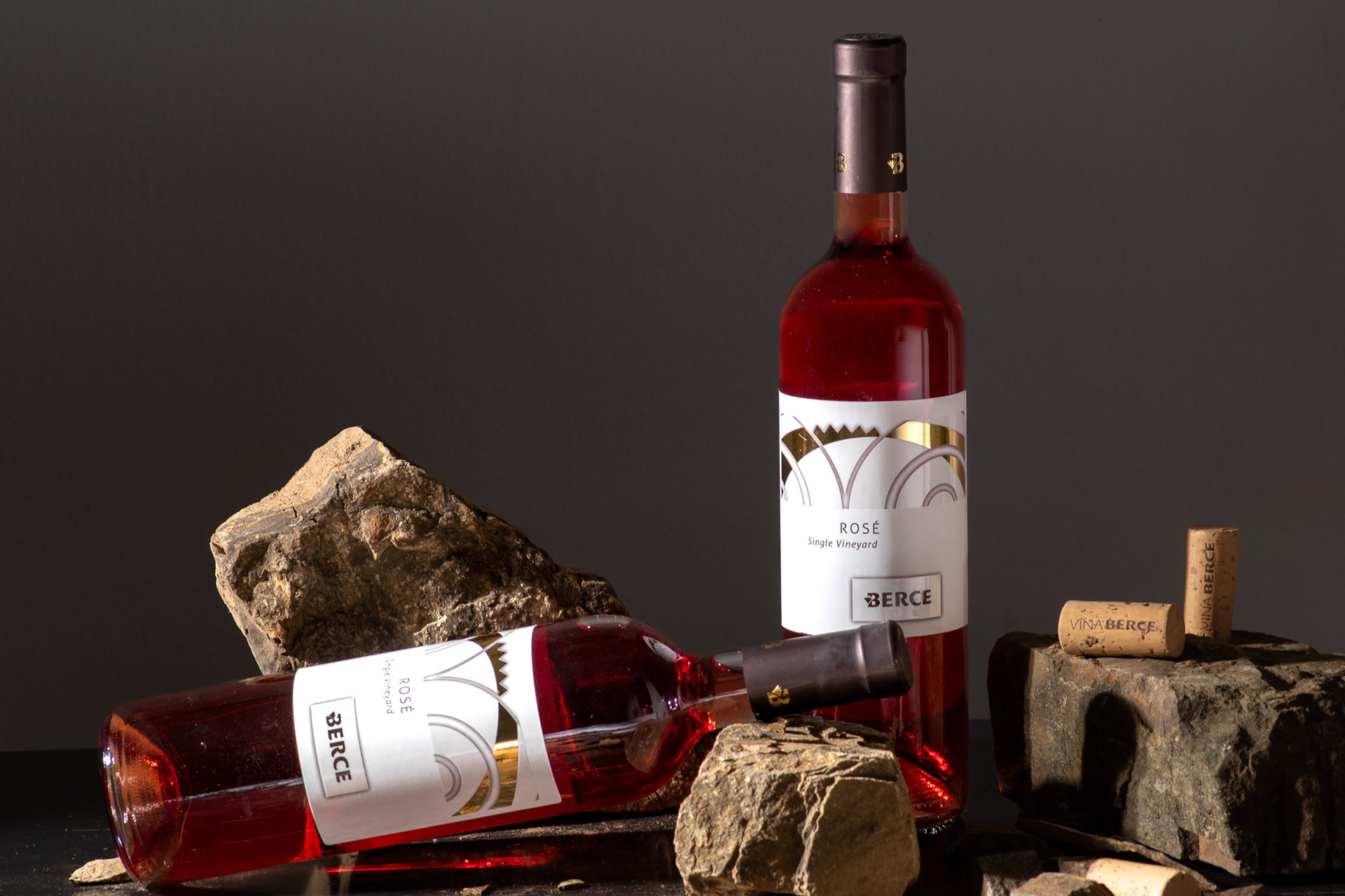 two bottles of rose with stones in dark setting