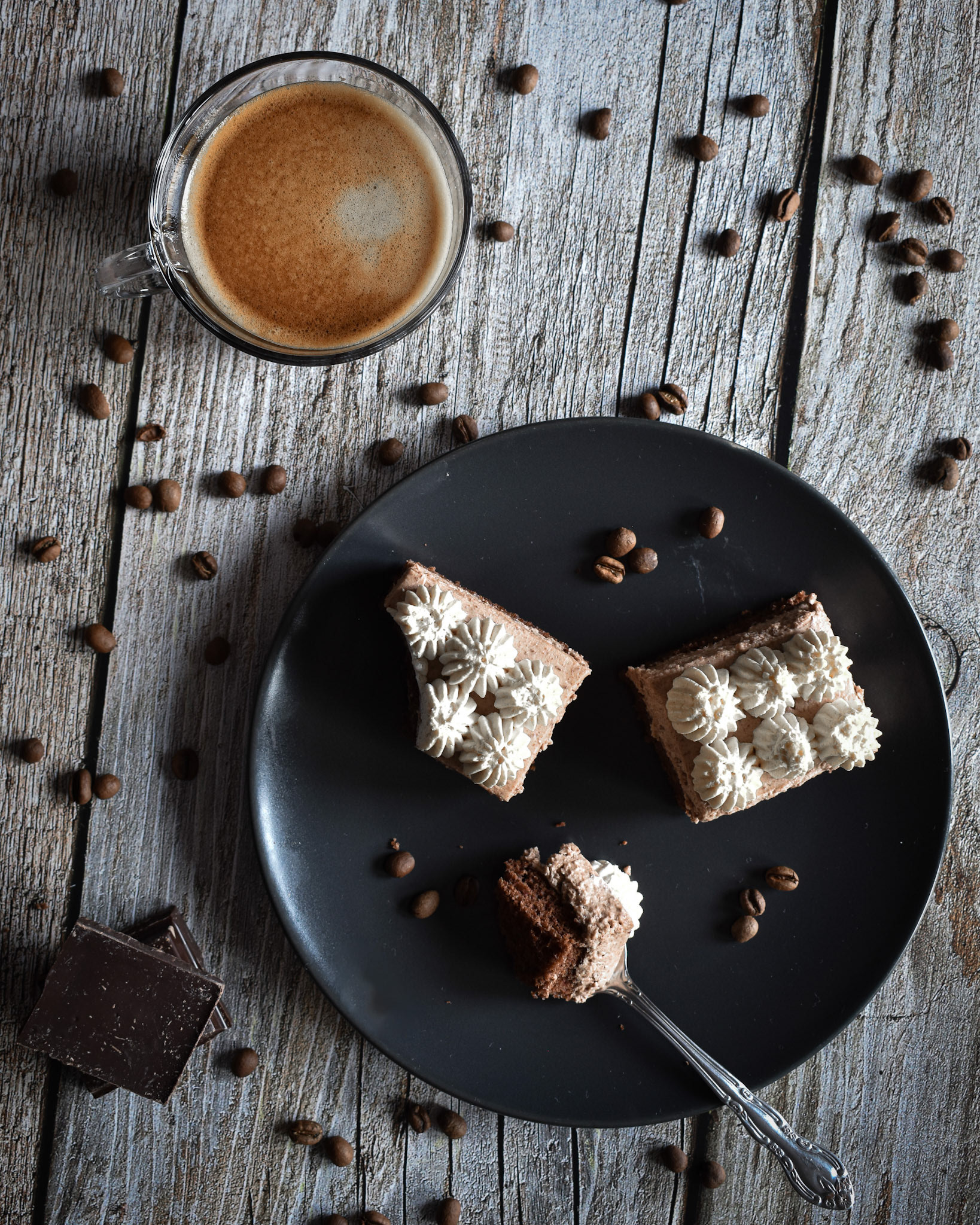 a cup of coffee, coffee beans and chocolate cream cake 