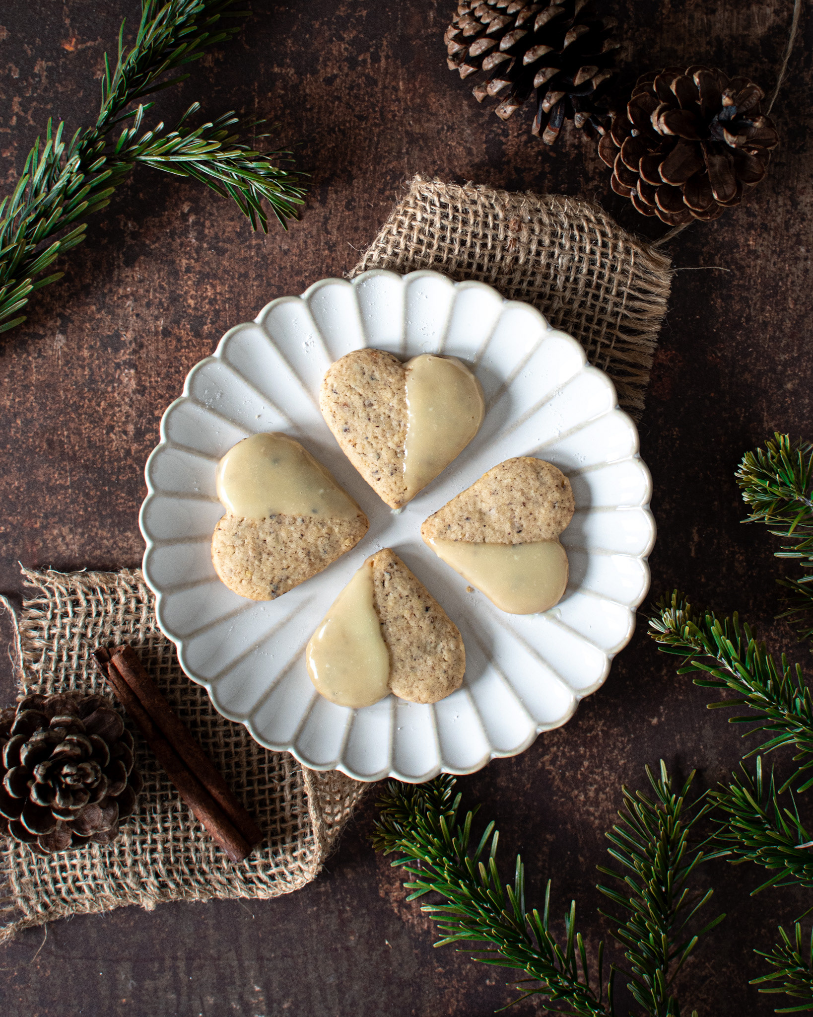 christmas cookies heart shaped, on a white plate with pine branches and pine cones