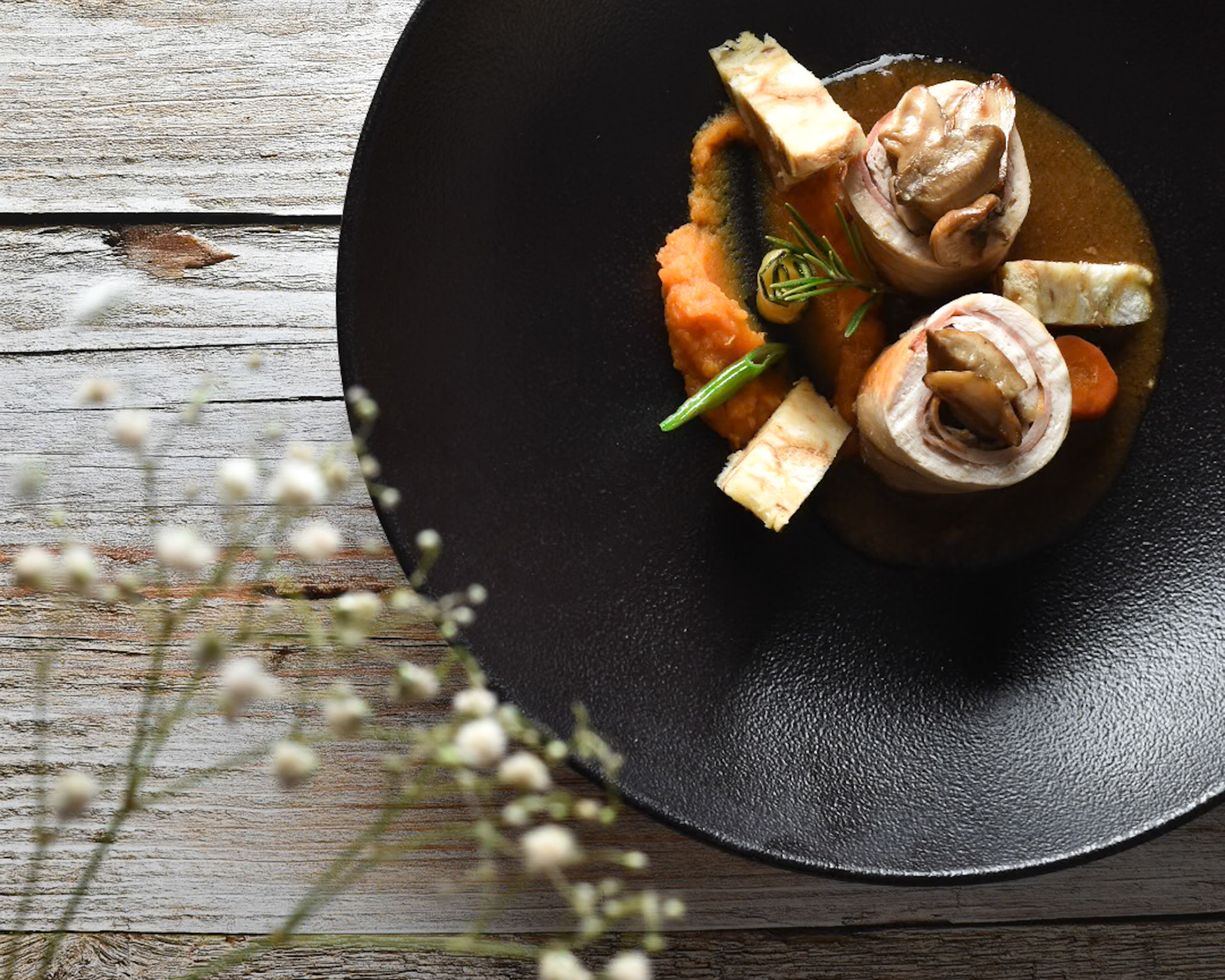 main dish from Domacija Marof, black plate, wood, dry flowers