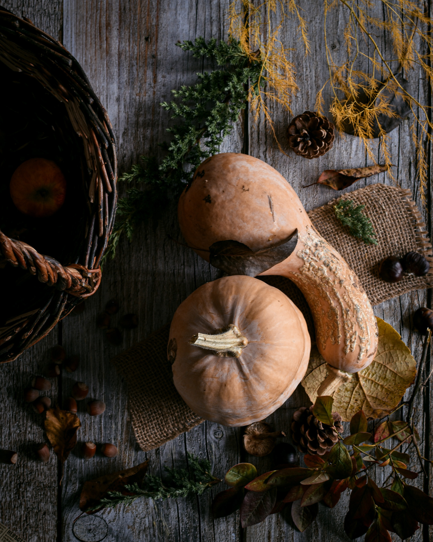 pumpkins, basket, hazelnuts, mushrooms, fall leasves on a wooden table