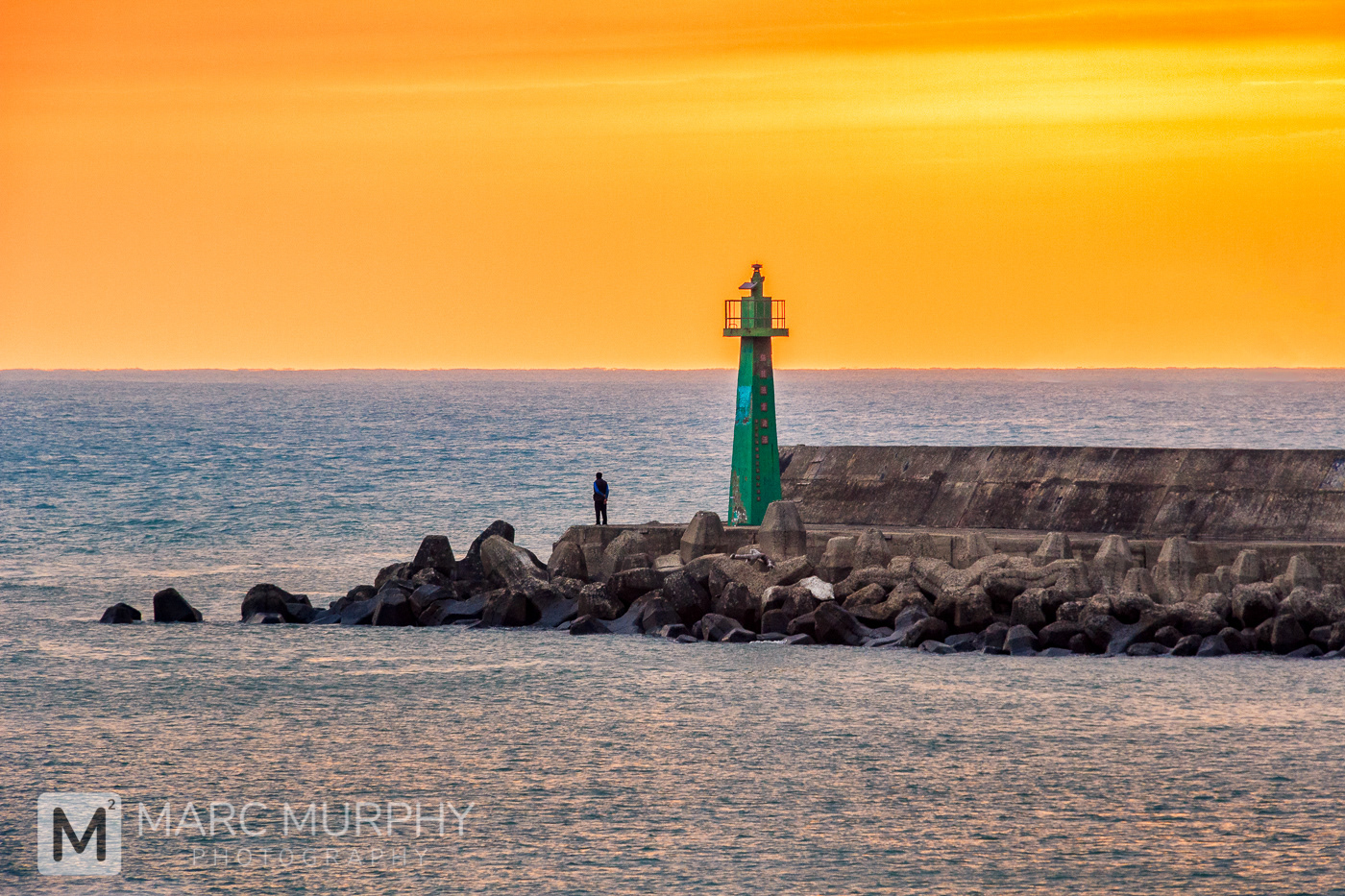 Taipei Taiwan Coastline Concrete Pier at Sunset with Lone Person, Green Painted Tower and Orange Sky