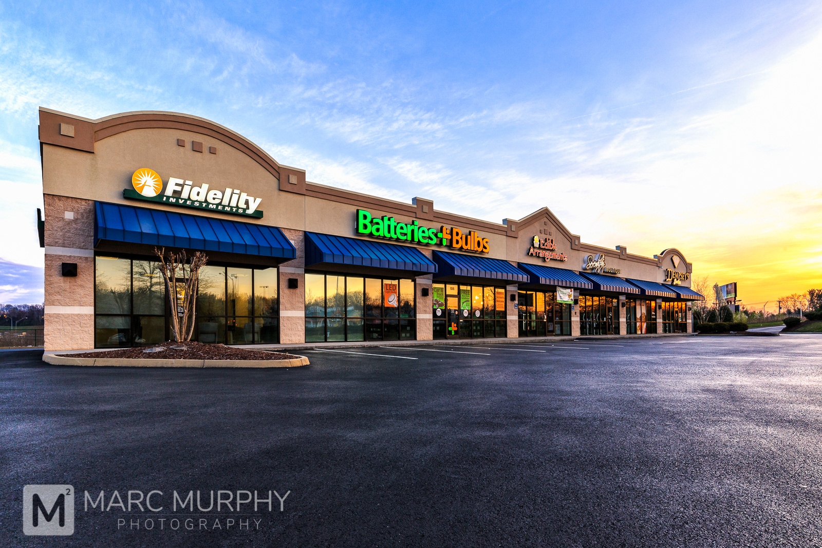 EFIS and Split-Faced Block Retail Shopping Center Exterior at Sunrise from Low Perspective with Yellow, Orange and Blue Sky