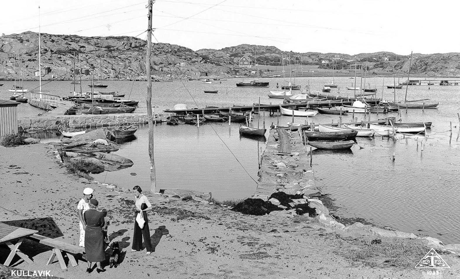 Ett välkänt vykort från 1938. Kullaviks hamn med "bonnabryggan" och en naturligt vuxen telefonstolpe. Okända personer på bilden.