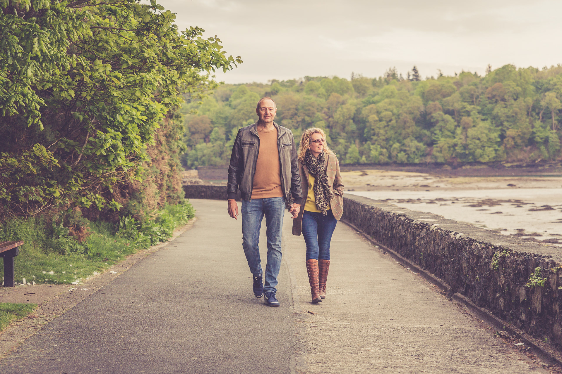 A couple portrait. The couple are walking hand in hand along the Belgian Promenade on Anglesey during a portrait photography session.