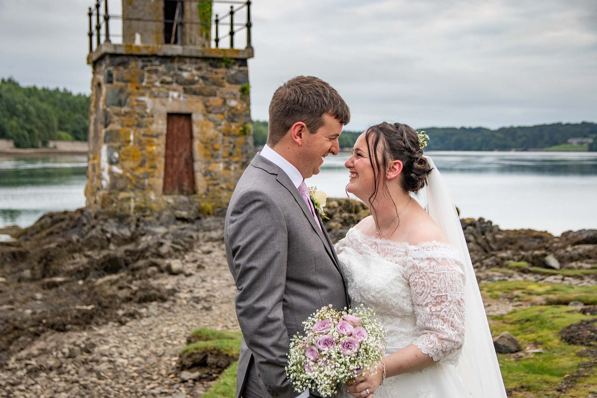 Wedding Photography. A bride and groom portrait taken on the banks of the Menai Straits near to Britannia bridge at Gwesty Garreg Bran Hotel