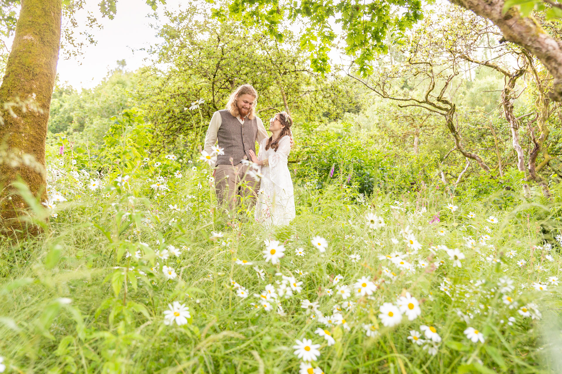 Bride and groom portrait at a woodland wedding in North Wales. A bride and groom standing looking at each other amongst wild flowers on their wedding day..