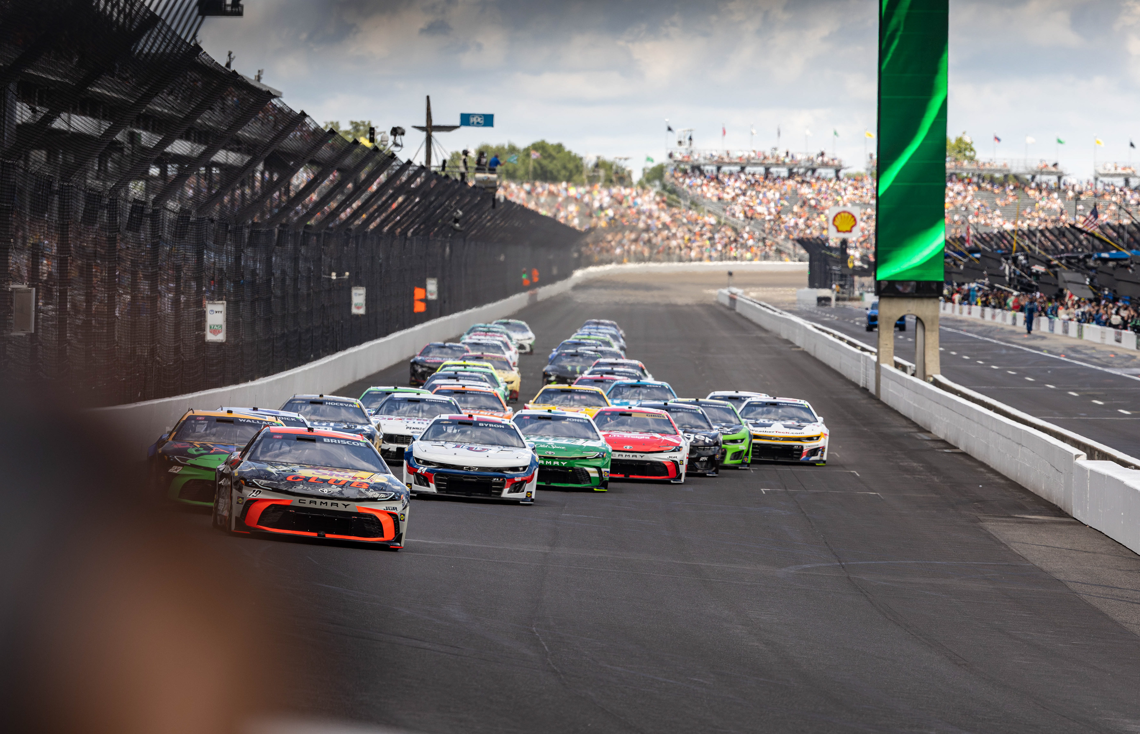 Chase Briscoe, driver of the No. 19 Toyota Camry for Joe Gibbs Racing in the NASCAR Cup Series, leads the field into Turn 1 on the first lap of the Brickyard 400, at the Indianapolis Motor Speedway, located in Speedway, Indiana, on July 27, 2025.