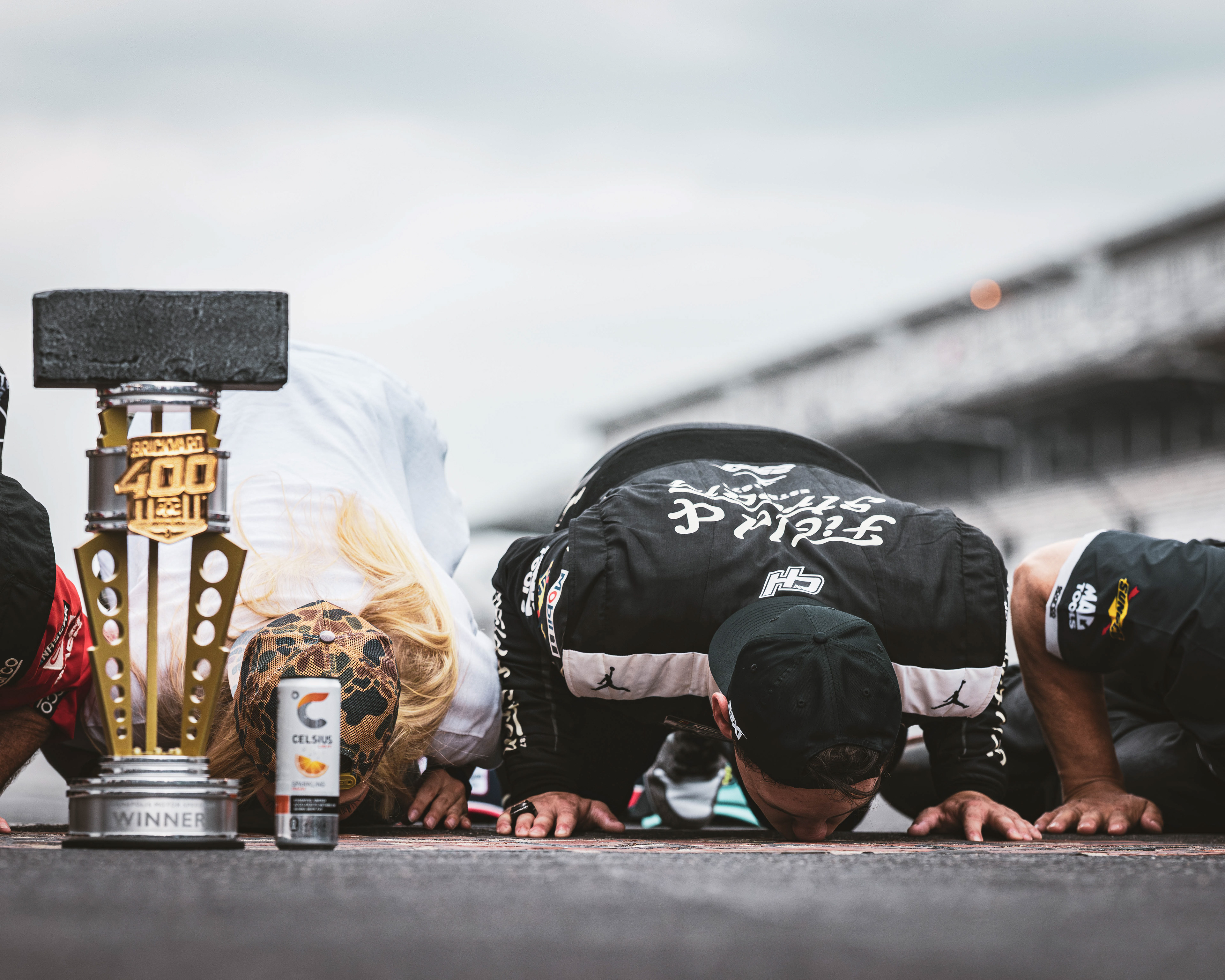 Corey Heim, driver of the No. 67 Toyota for 23XI Racing, kisses the bricks on the frontstretch after winning the Brickyard 400 at Indianapolis Motor Speedway.