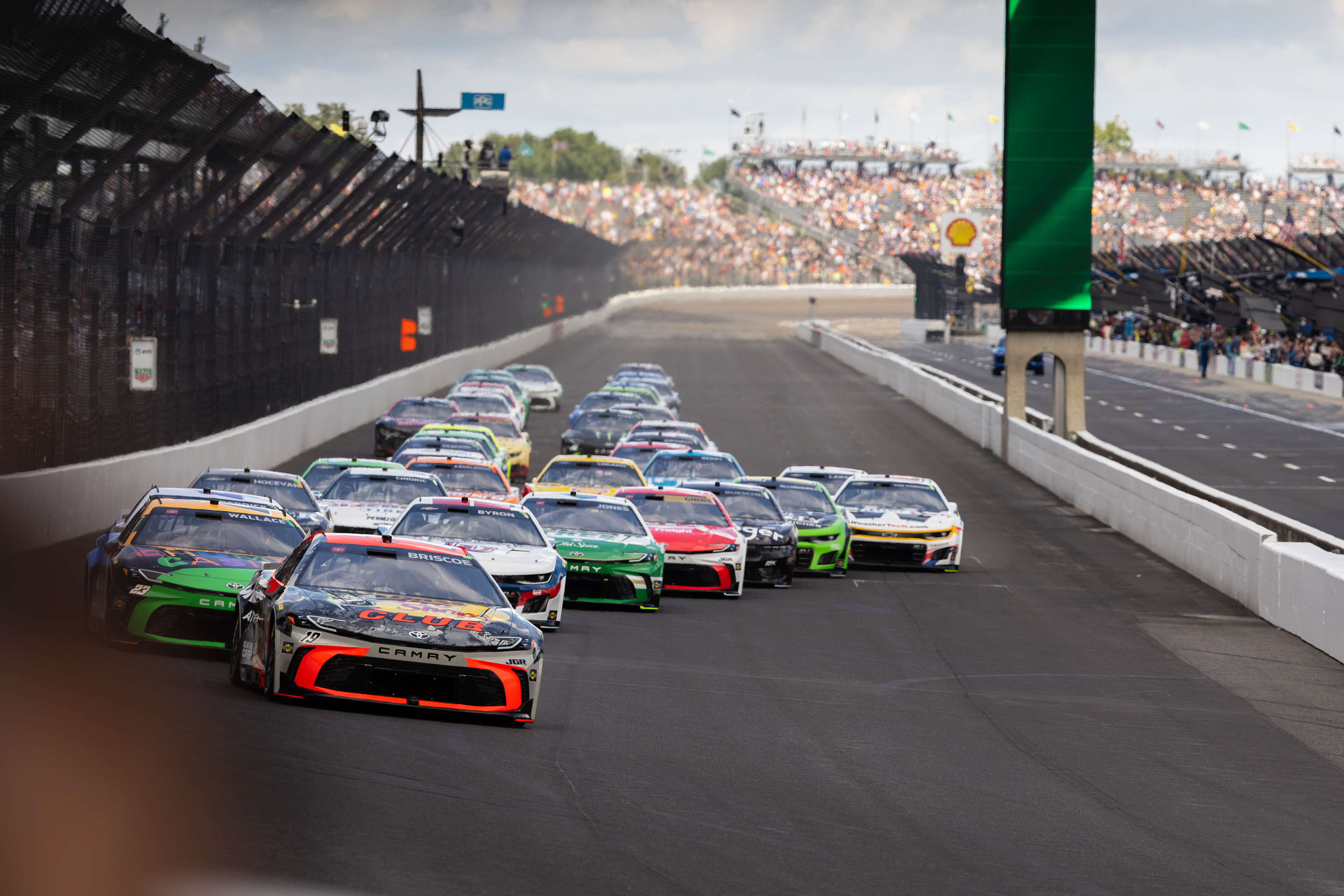 Chase Briscoe, driver of the No. 19 Toyota Camry for Joe Gibbs Racing in the NASCAR Cup Series, leads the field into Turn 1 on the first lap of the Brickyard 400, at the Indianapolis Motor Speedway, located in Speedway, Indiana, on July 27, 2025.