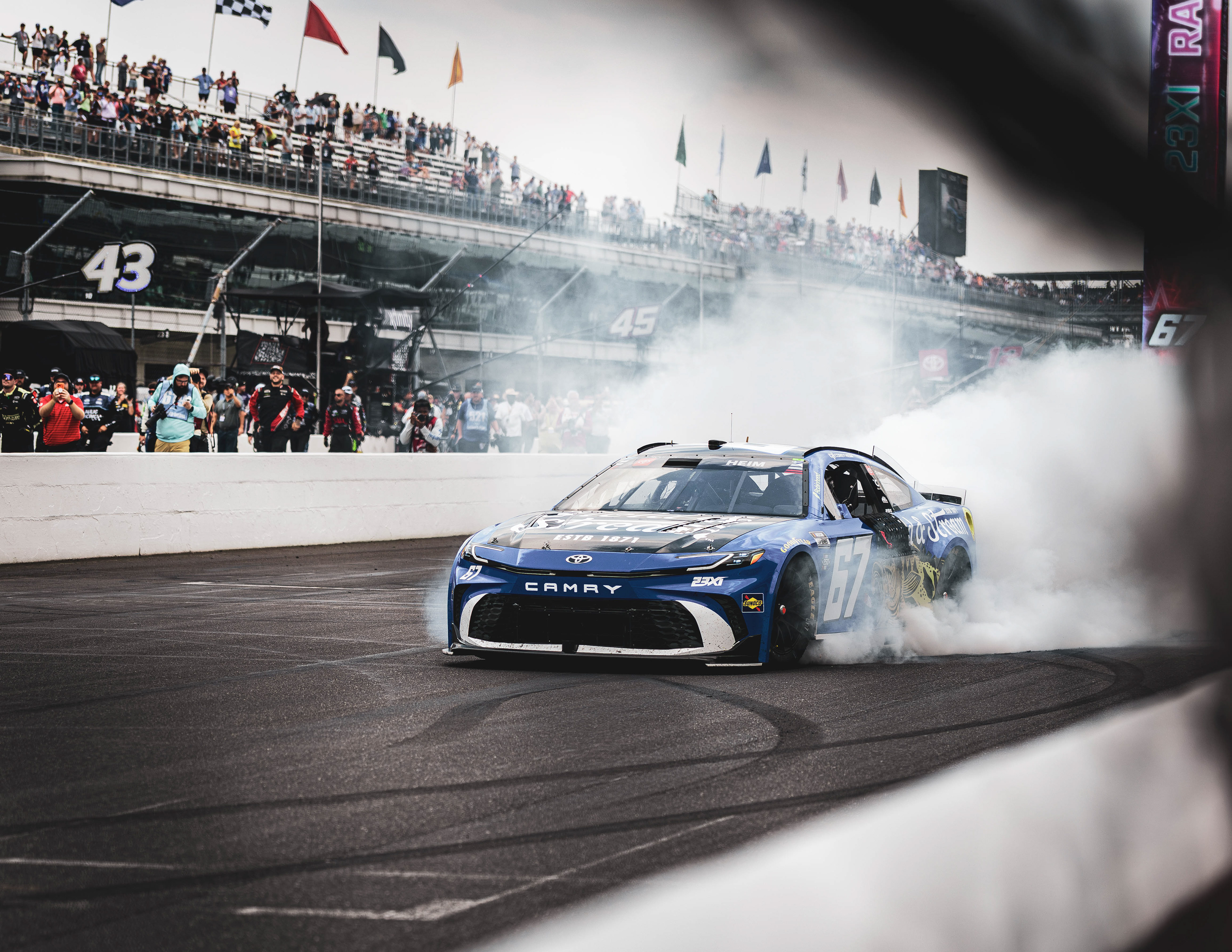Corey Heim, driver of the No. 67 Toyota for 23XI Racing, does a burnout on the frontstretch after winning the Brickyard 400 at Indianapolis Motor Speedway.