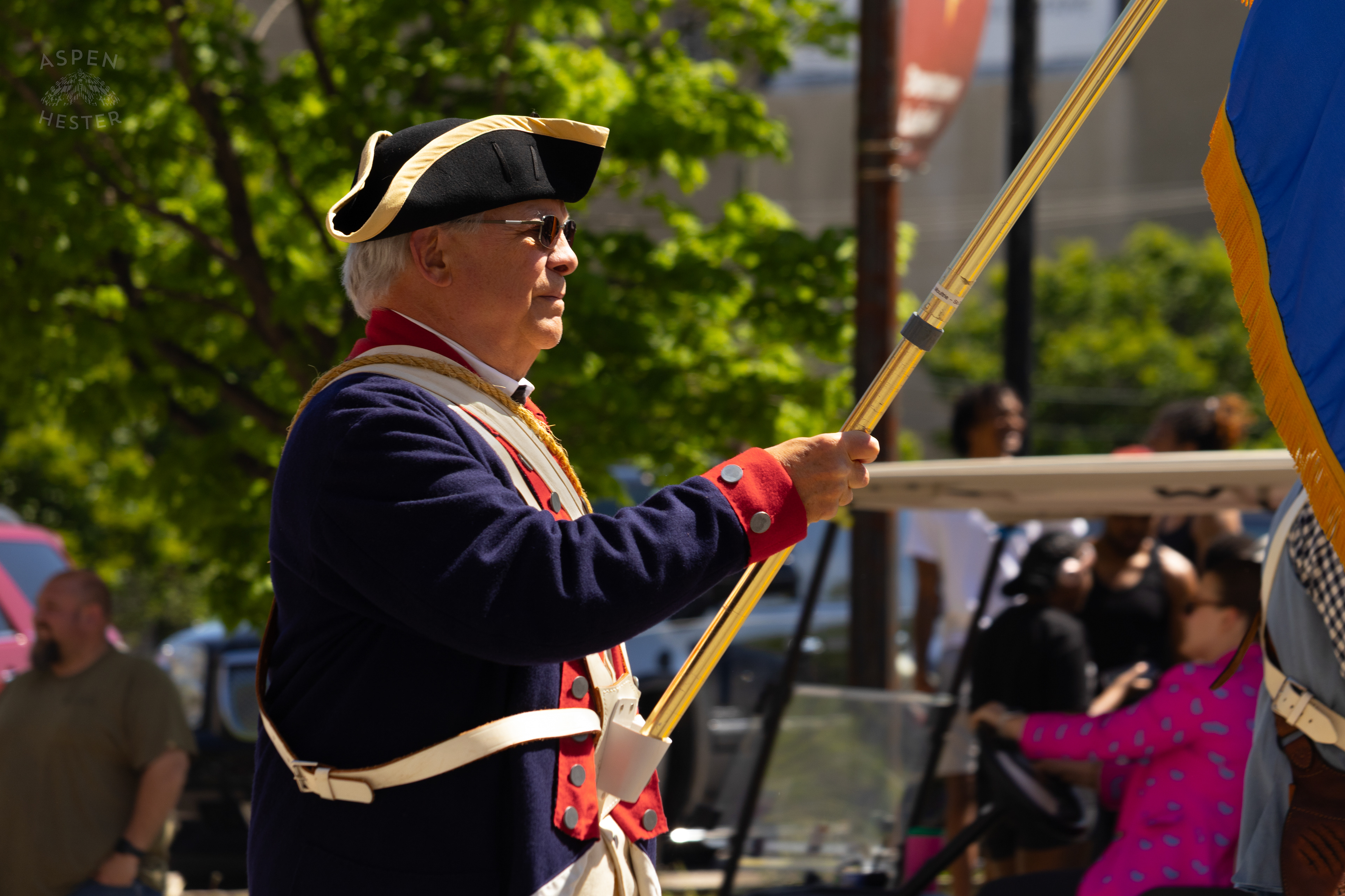 A Flag Bearer of The Sons of The American Revolution Plays as He Walks Down West Broadway  for The 70th Annual Pegasus Parade. April 27th, 2025/Aspen Hester