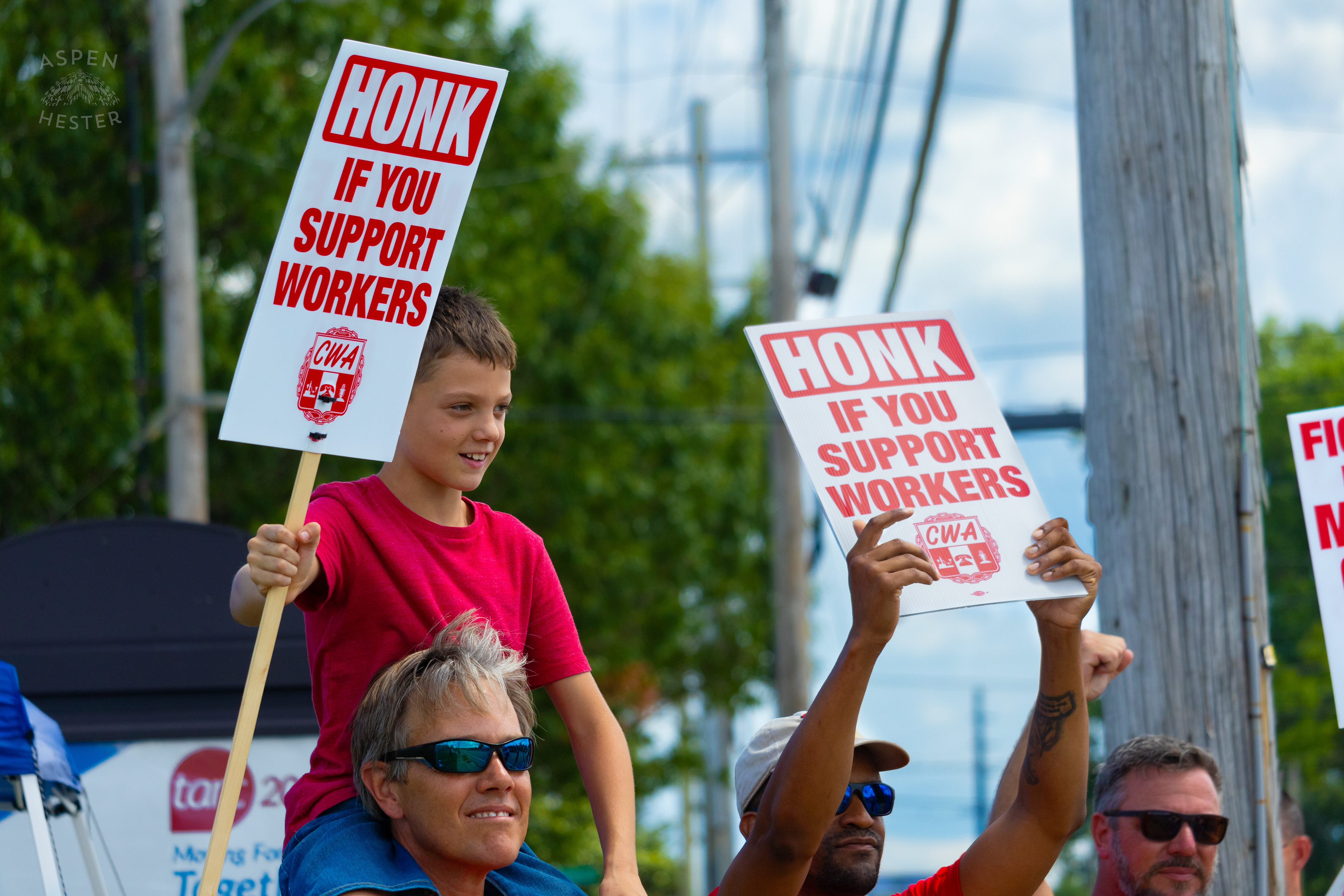 Member of The Communication Workers of America Union Hoists An Enthused Child onto Their Shoulders While Striking Against AT&T for Fair Pay and Benefits. August 18th, 2024/Aspen Hester