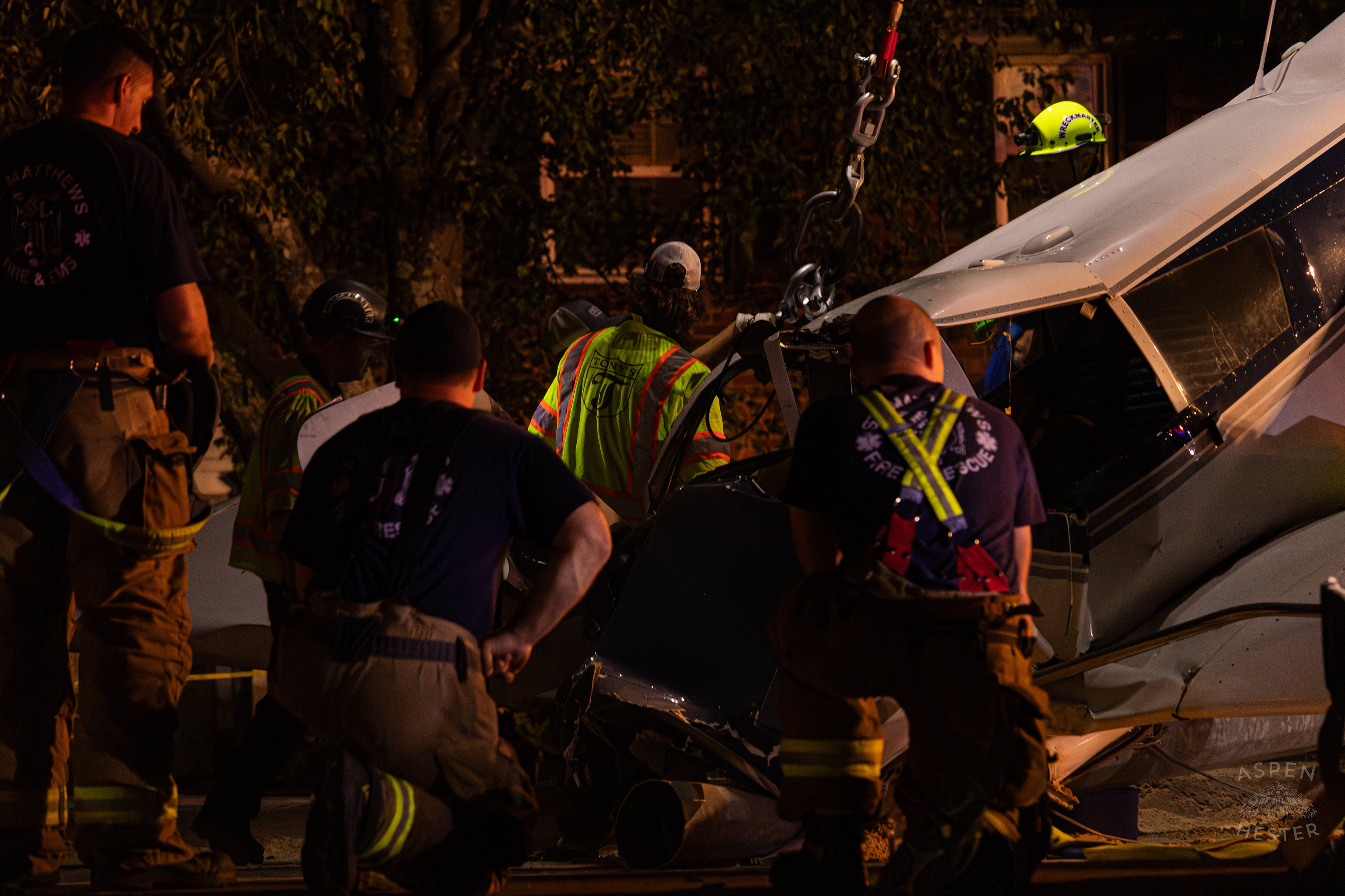St. Matthews Firefighters Kneeling in Respect as A Crane from Tony’s Wreckers Removes The Piper Cherokee Plane from the Road after it Crash Landed, Taking Out Utility Poles, and Hitting A Car on Breckenridge Lane and Kresge Way. October 11th, 2024/Aspen Hester 