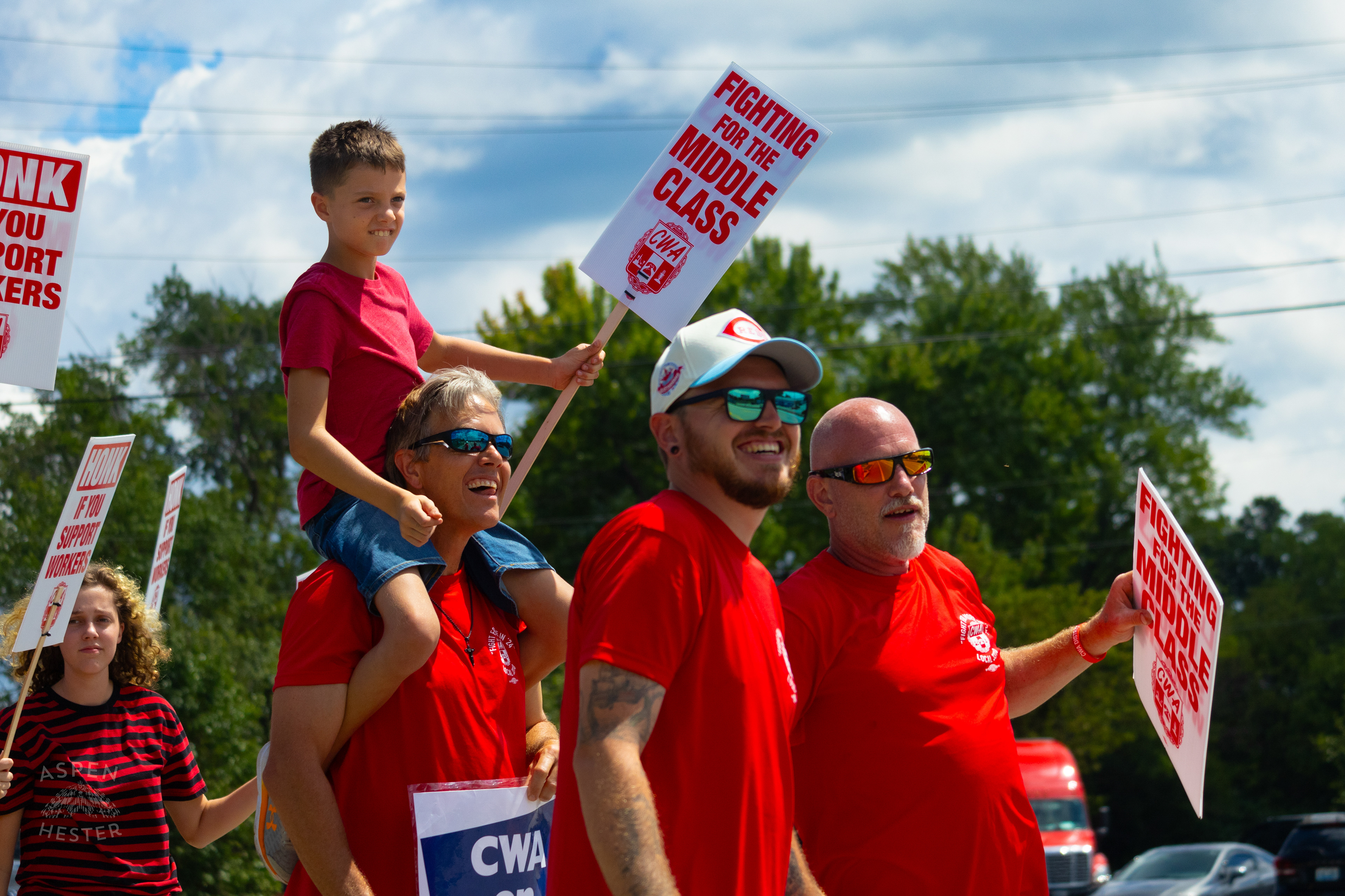 Member of The Communication Workers of America Union Hoists An Enthused Child onto Their Shoulders While Striking Against AT&T for Fair Pay and Benefits. August 18th, 2024/Aspen Hester