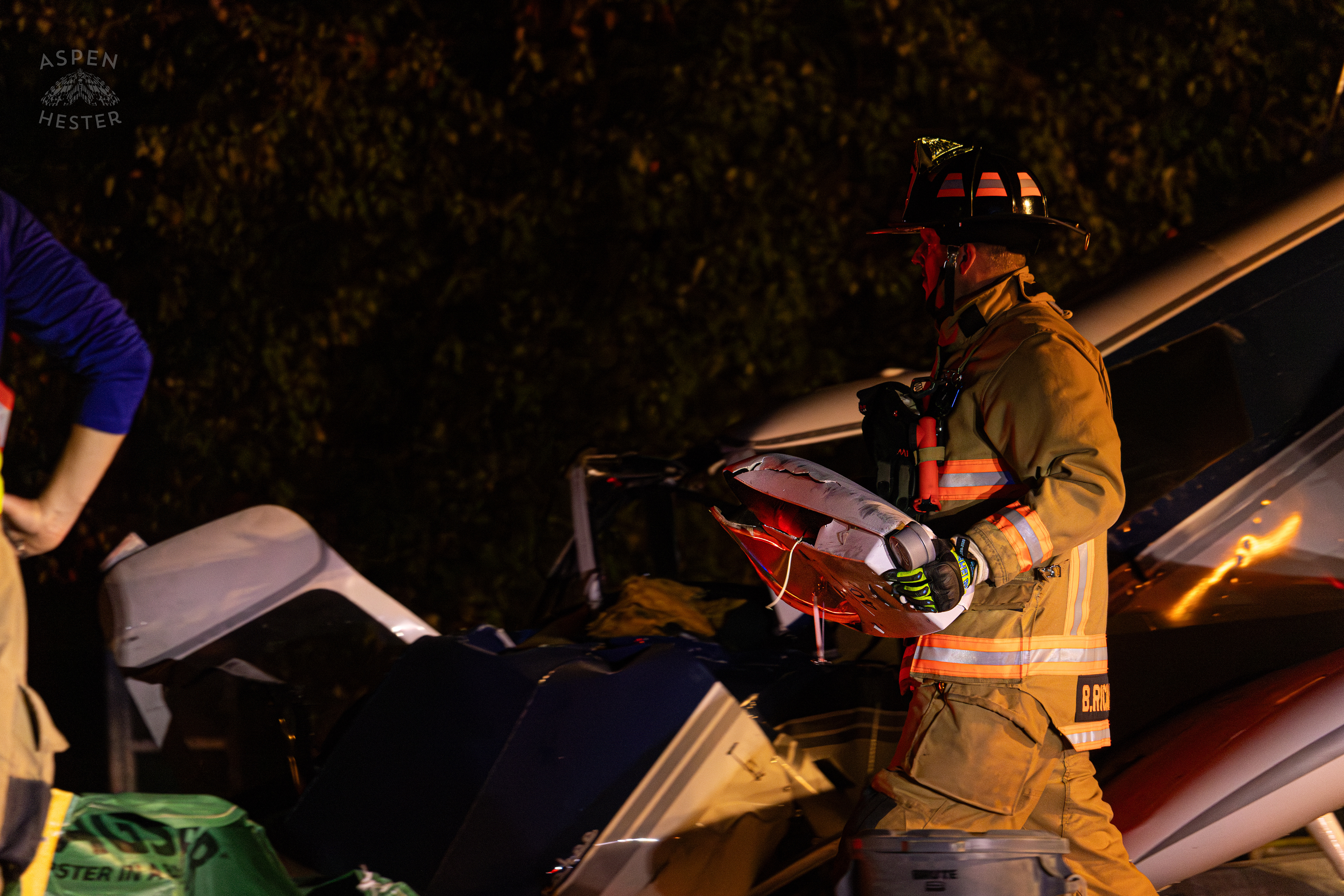 St. Matthews Firefighter Carrying A Street Light to The Debris Pile so A Crew from Tony’s Wreckers Can Begin Removing The Piper Cherokee Plane from the Road after it Crash Landed, Taking Out Utility Poles, and Hitting A Car on Breckenridge Lane and Kresge Way. October 11th, 2024/Aspen Hester 