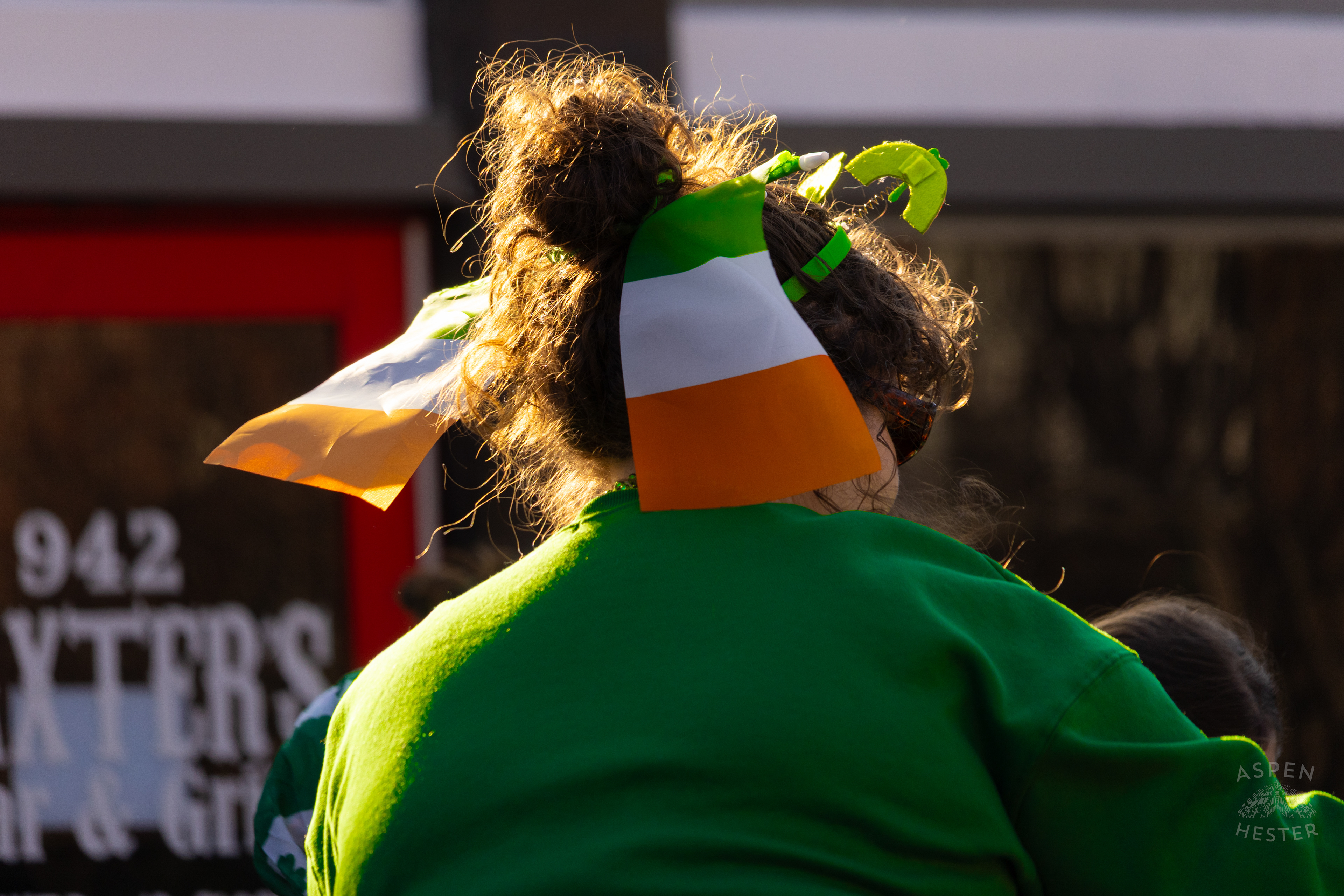 Participant with Two Irish Flags Poking of Their Hair as The 52nd Annual Saint Patrick’s Day Parade Rolls Through The Highlands. March 8th, 2025/Aspen Hester