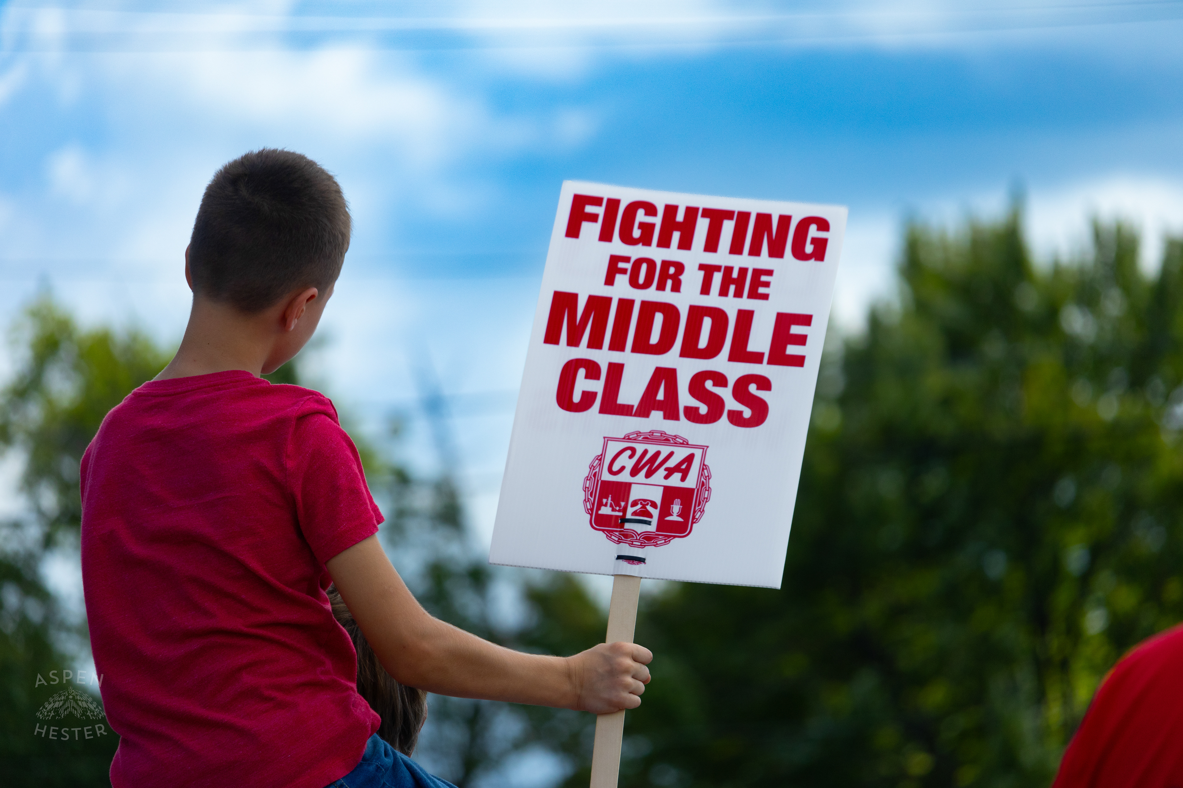 Member of The Communication Workers of America Union Hoists An Enthused Child onto Their Shoulders While Striking Against AT&T for Fair Pay and Benefits. August 18th, 2024/Aspen Hester