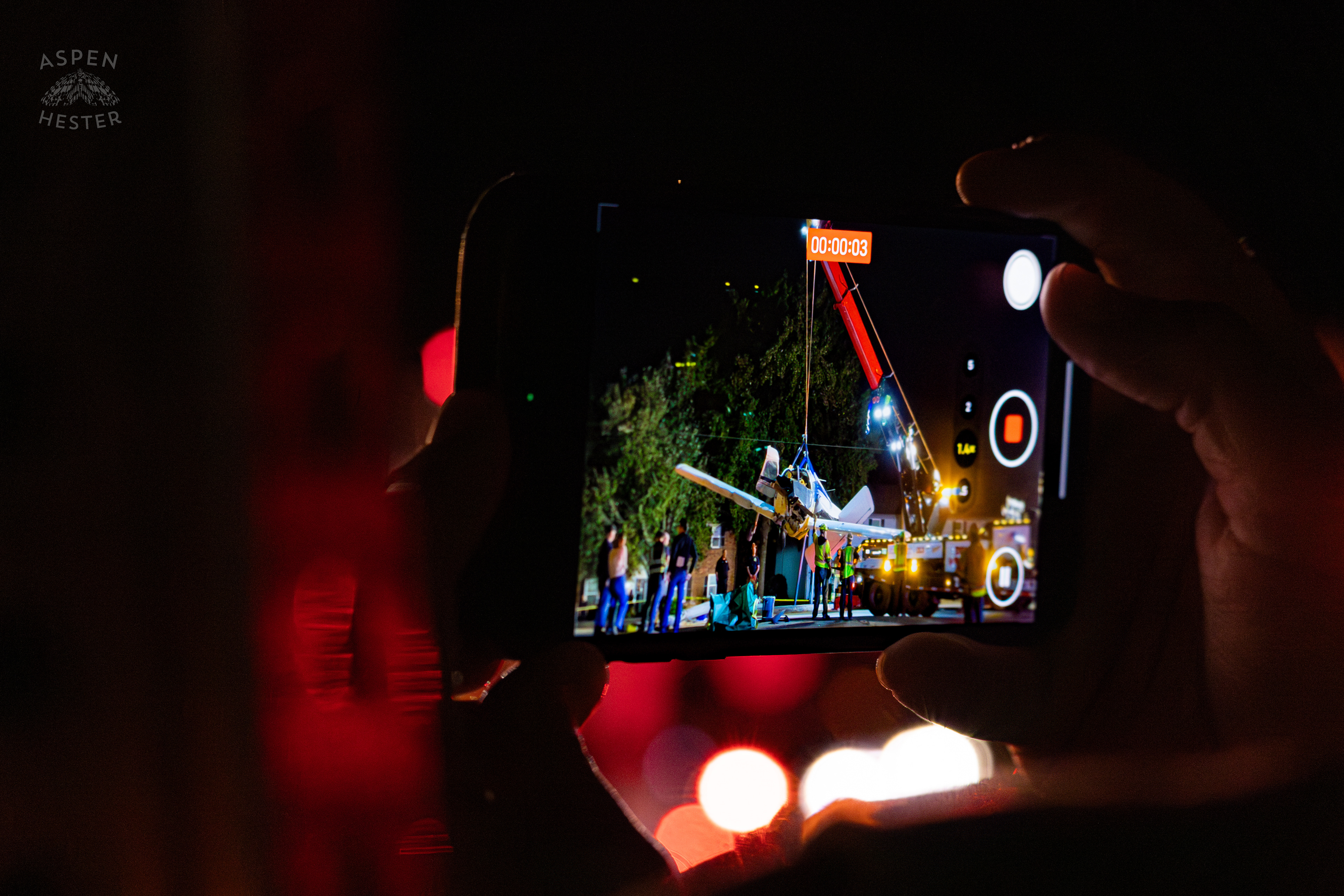 View from An Onlookers Phone as Tony's Wreckers Crew Works to Remove The Piper Cherokee Plane from the Road after it Crash Landed, Taking Out Utility Poles, and Hitting A Car on Breckenridge Lane and Kresge Way. October 11th, 2024/Aspen Hester