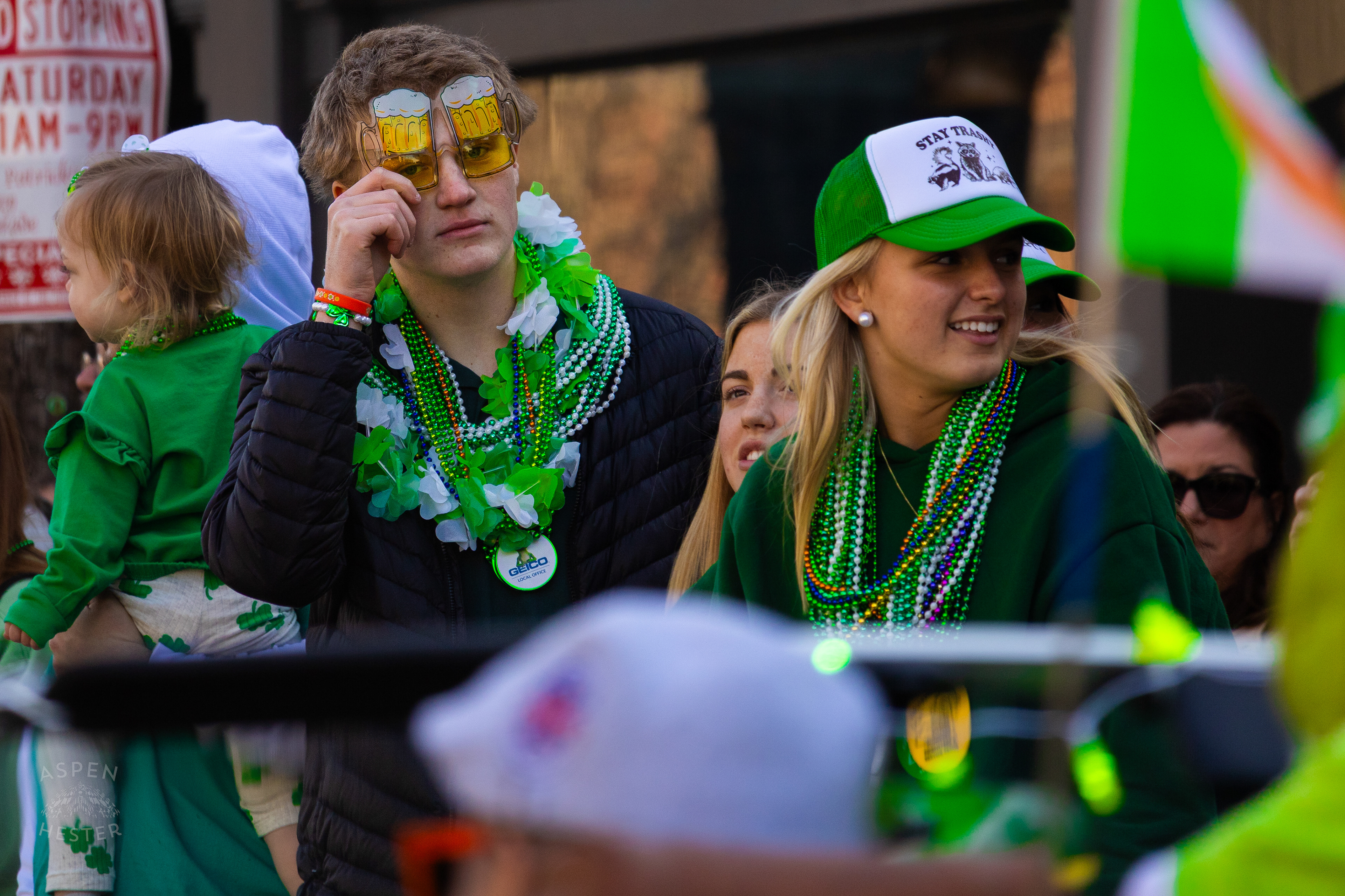 A Spectator Decked Out in Beads and Beer Glasses Watches as The 52nd Annual Saint Patrick’s Day Parade Rolls Through The Highlands. March 8th, 2025/Aspen Hester
