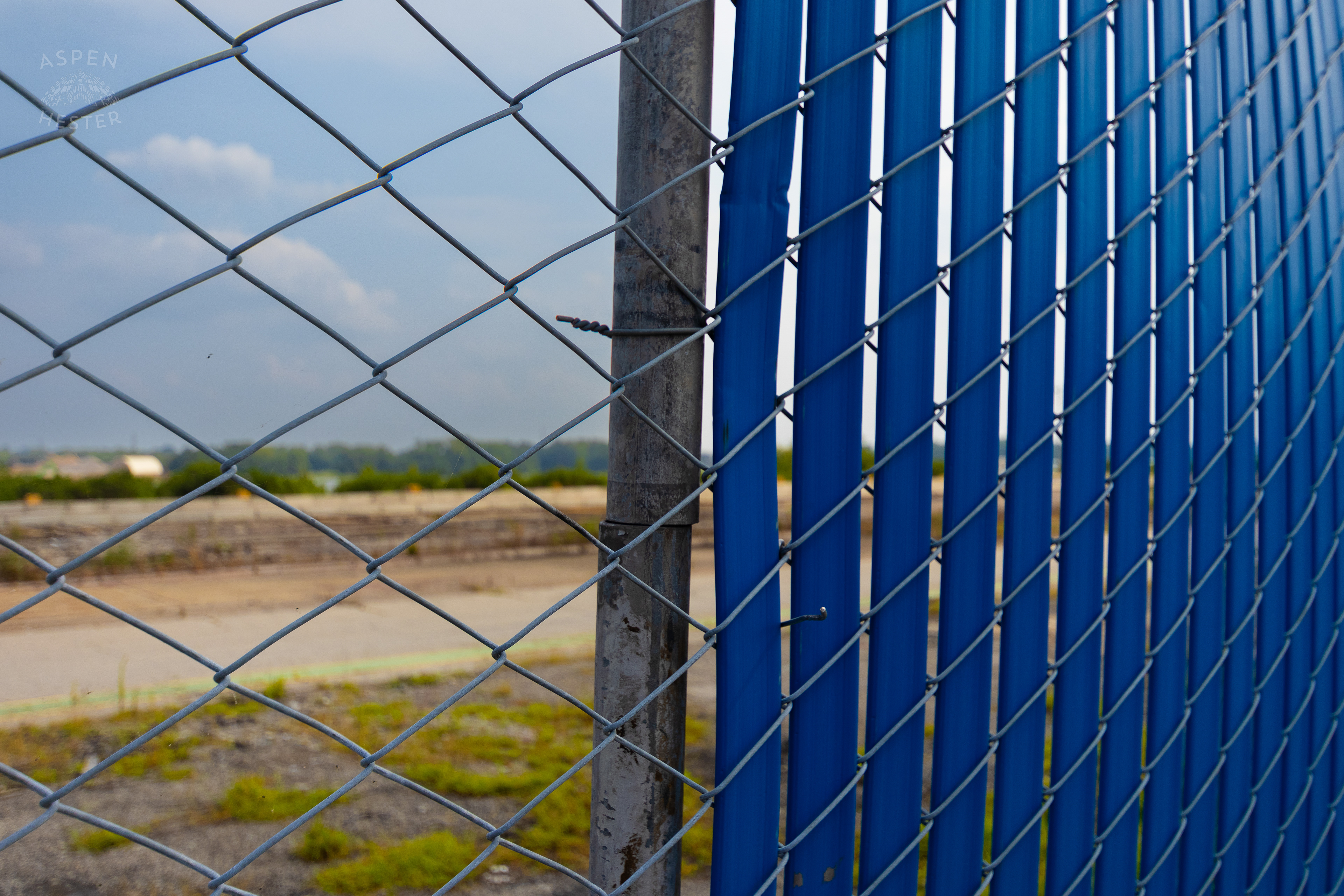 Looking Through the Chain Link Fence and Blue Tarp at the Abandoned Jeffboat Shipyard. July 26th, 2024/Aspen Hester