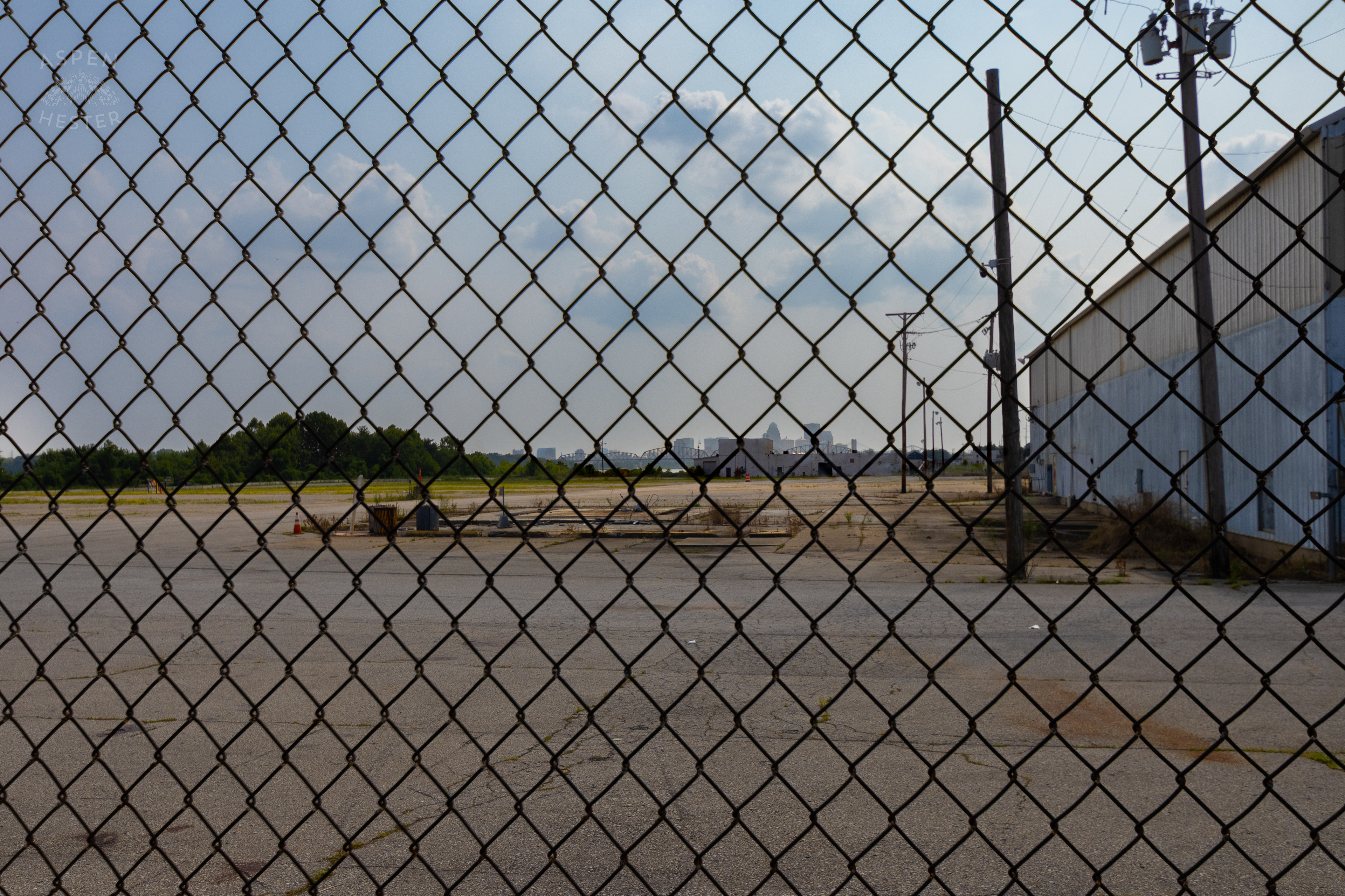 Looking Through the Chain Link Fence at the Abandoned Jeffboat Shipyard. July 26th, 2024/Aspen Hester