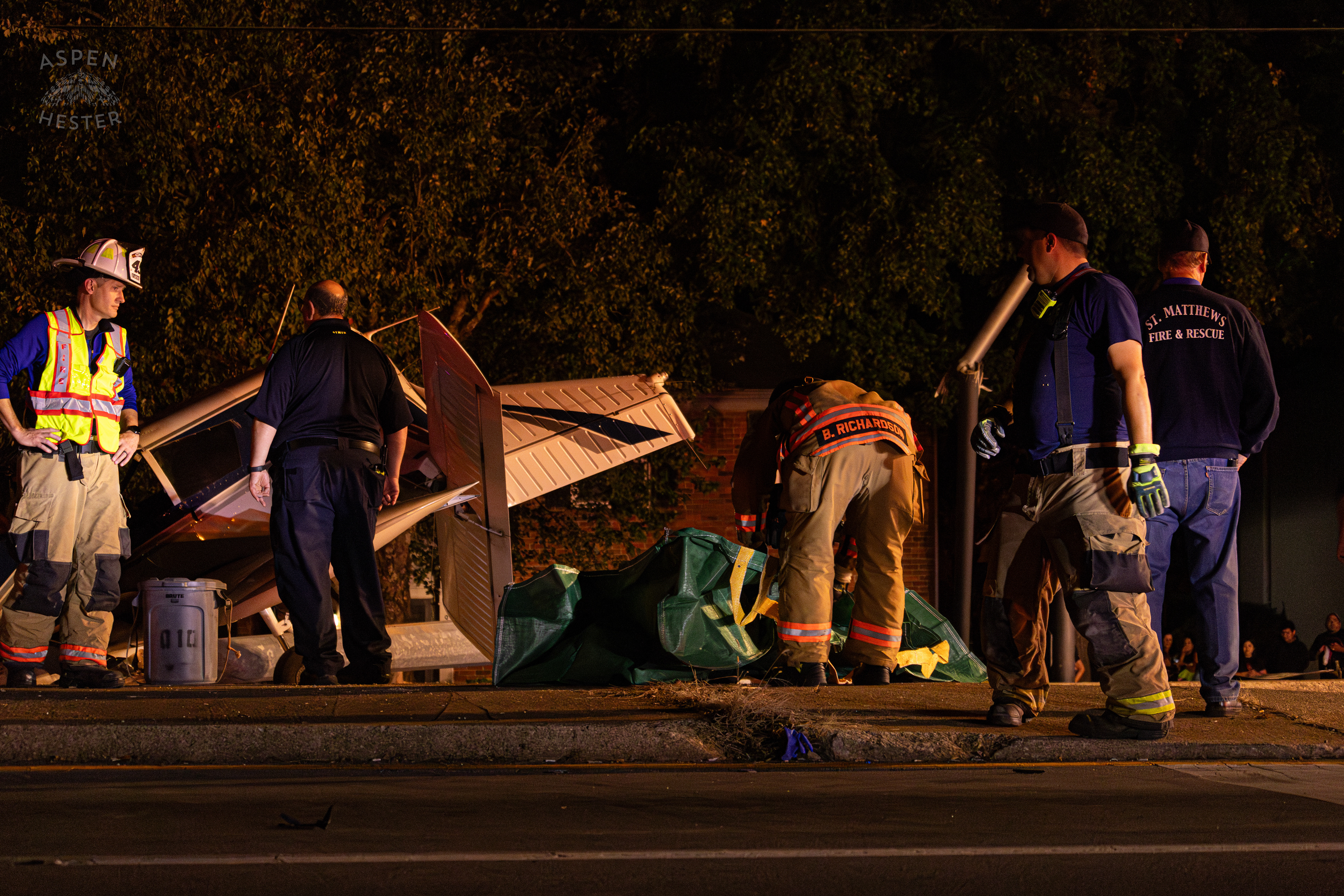 St. Matthews Firefighters Clearing The Scene so A Crew from Tony’s Wreckers Can Begin Removing The Piper Cherokee Plane from the Road after it Crash Landed, Taking Out Utility Poles, and Hitting A Car on Breckenridge Lane and Kresge Way. October 11th, 2024/Aspen Hester 