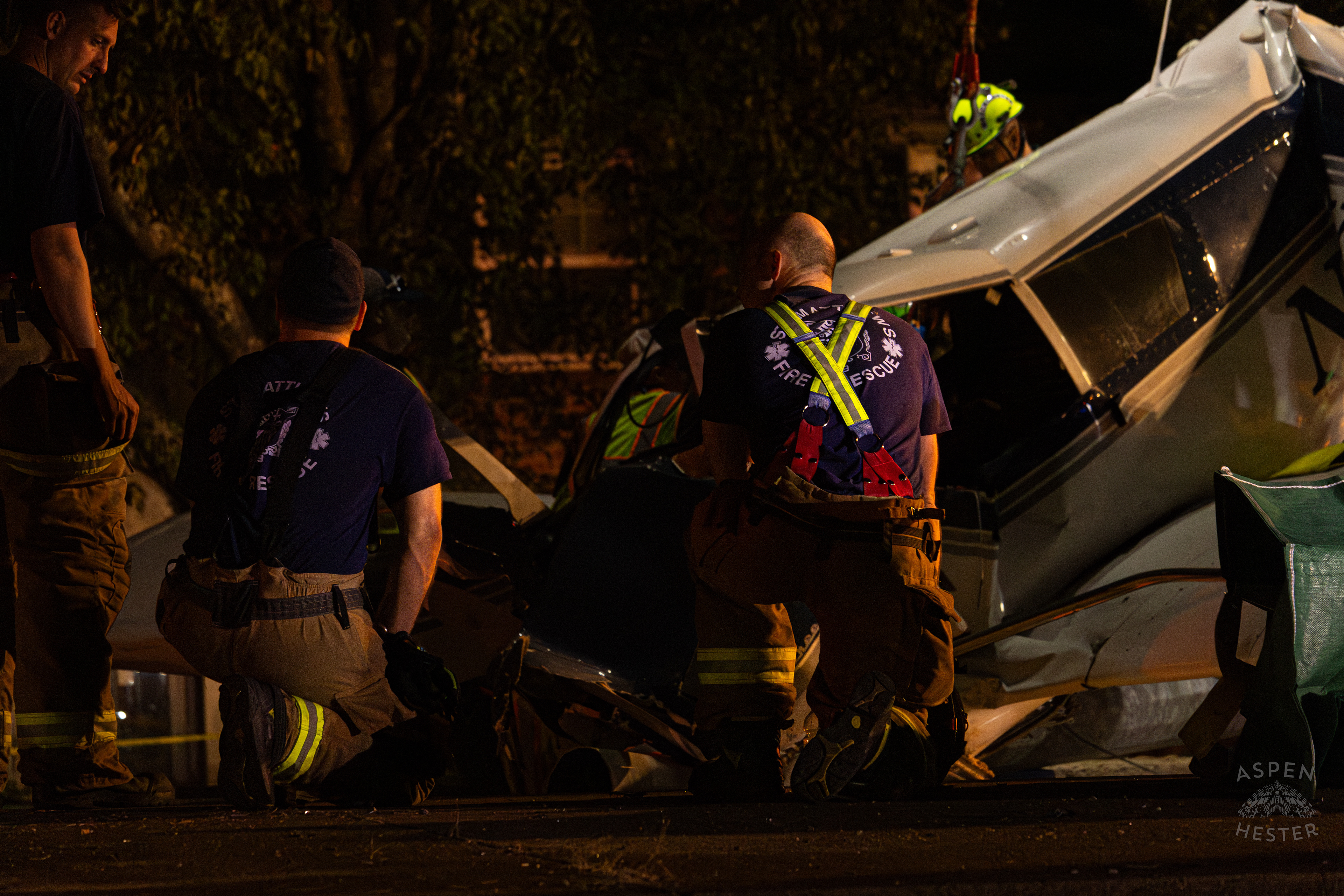 St. Matthews Firefighters Kneeling in Respect as A Crane from Tony’s Wreckers Removes The Piper Cherokee Plane from the Road after it Crash Landed, Taking Out Utility Poles, and Hitting A Car on Breckenridge Lane and Kresge Way. October 11th, 2024/Aspen Hester 