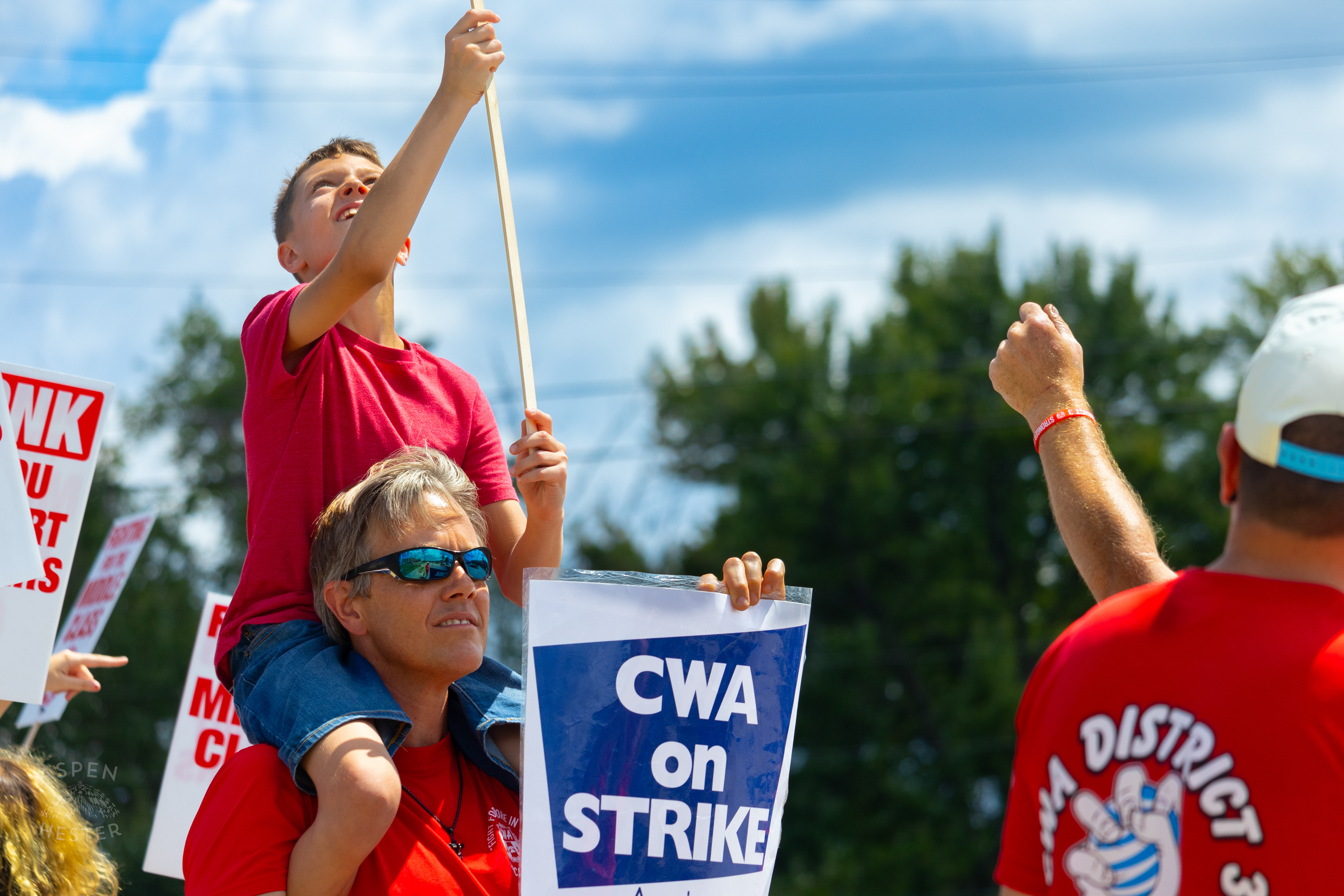 Member of The Communication Workers of America Union Hoists An Enthused Child onto Their Shoulders While Striking Against AT&T for Fair Pay and Benefits. August 18th, 2024/Aspen Hester