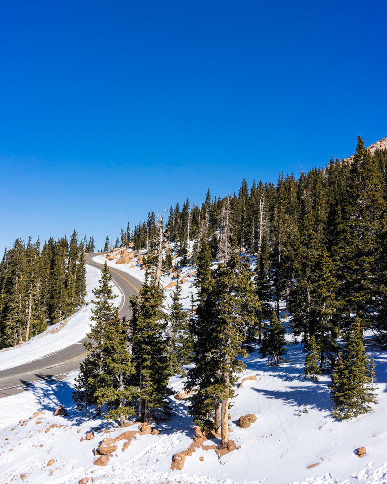A winding road through the ever greens to the top of Pike's Peak in Colorado Spring, CO. A fresh blanket of snow covers the rocks.