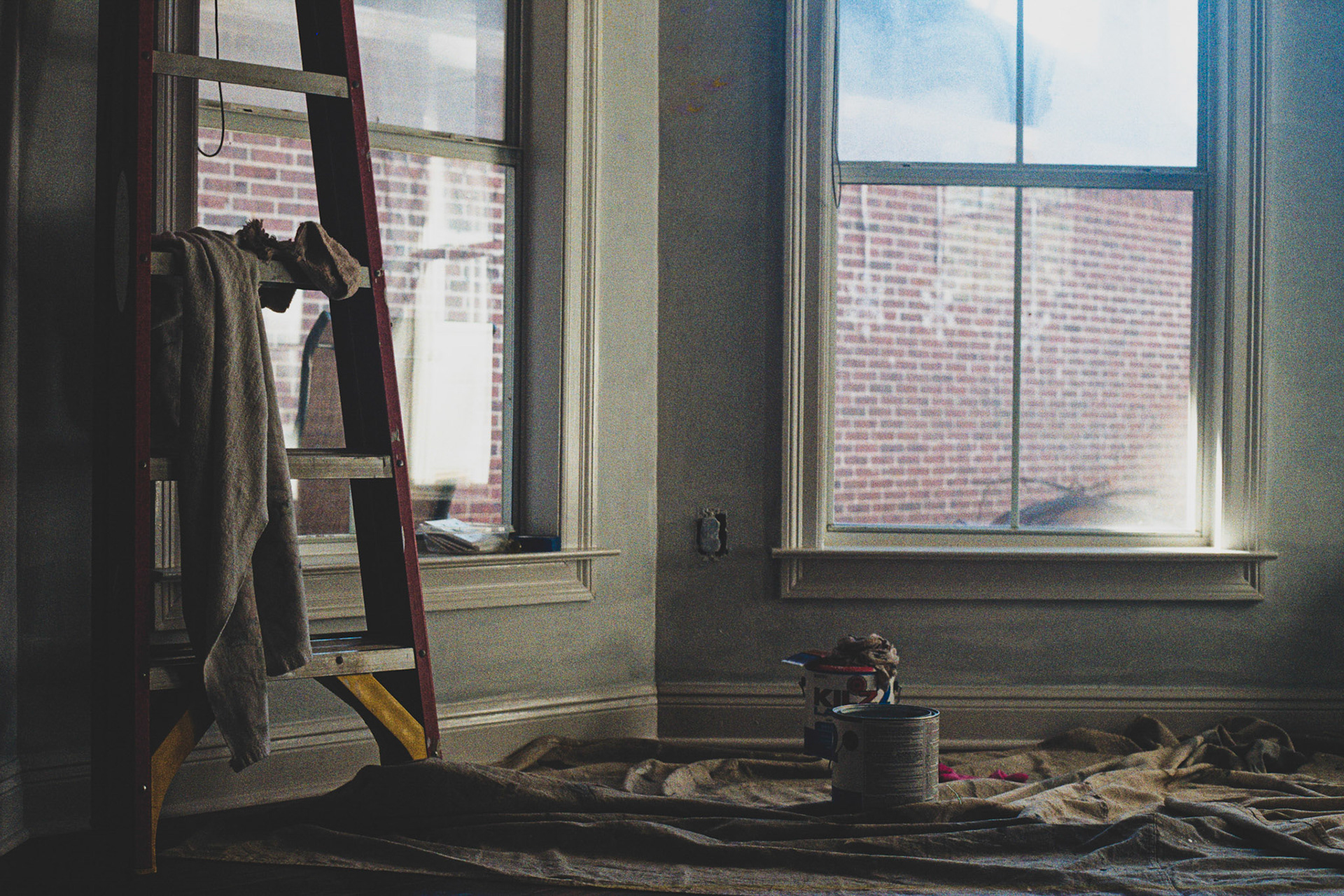 A cloth tarp covers the floor with two paint cans and a Latter. It is time for some home improvment. It is painting day.