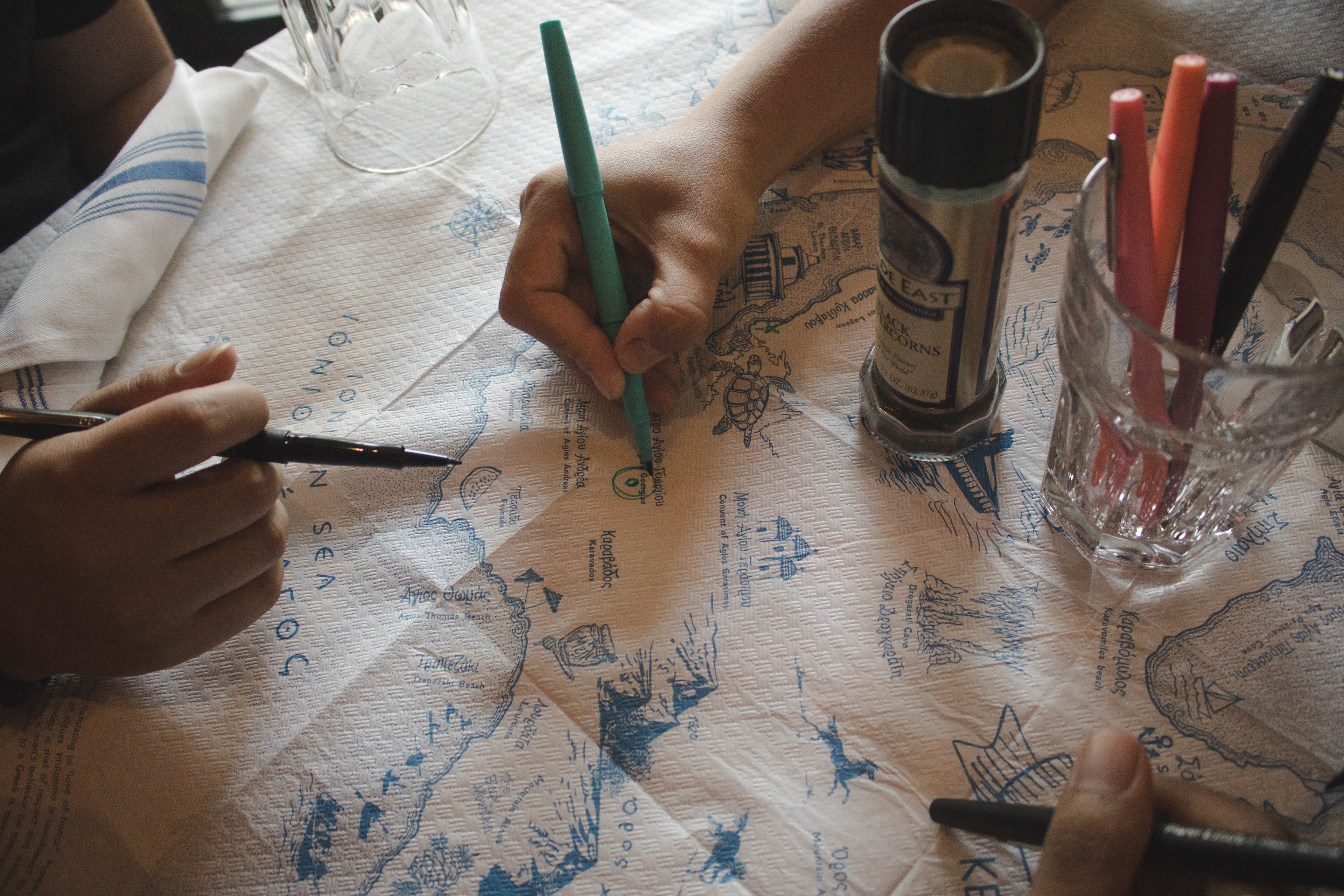 People interacting and drawing on the tablecloth during mealtime.