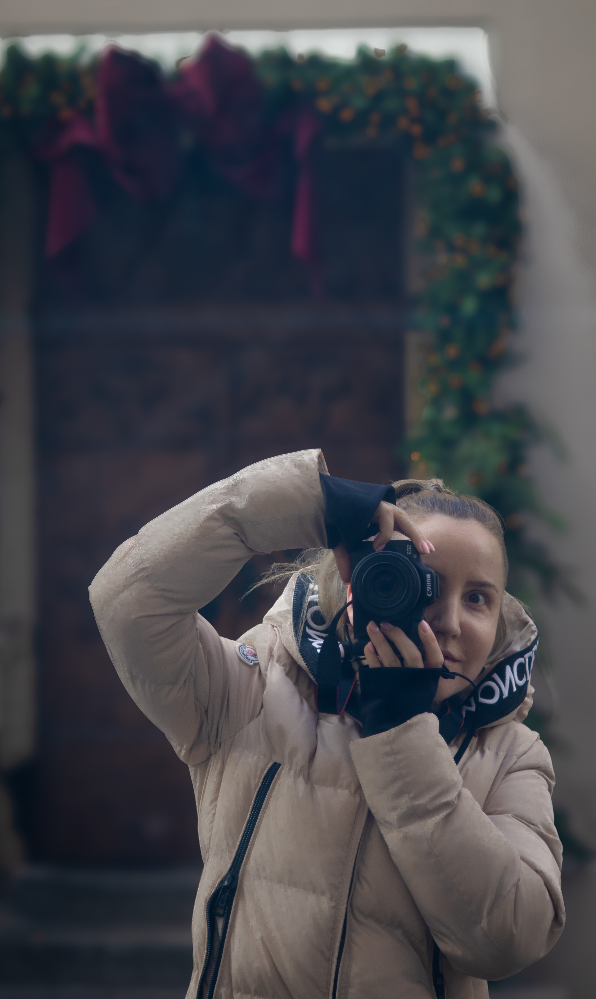 Imagine cu o fotografă ce se pozează în vitrină cu camera sa foto, Canon.