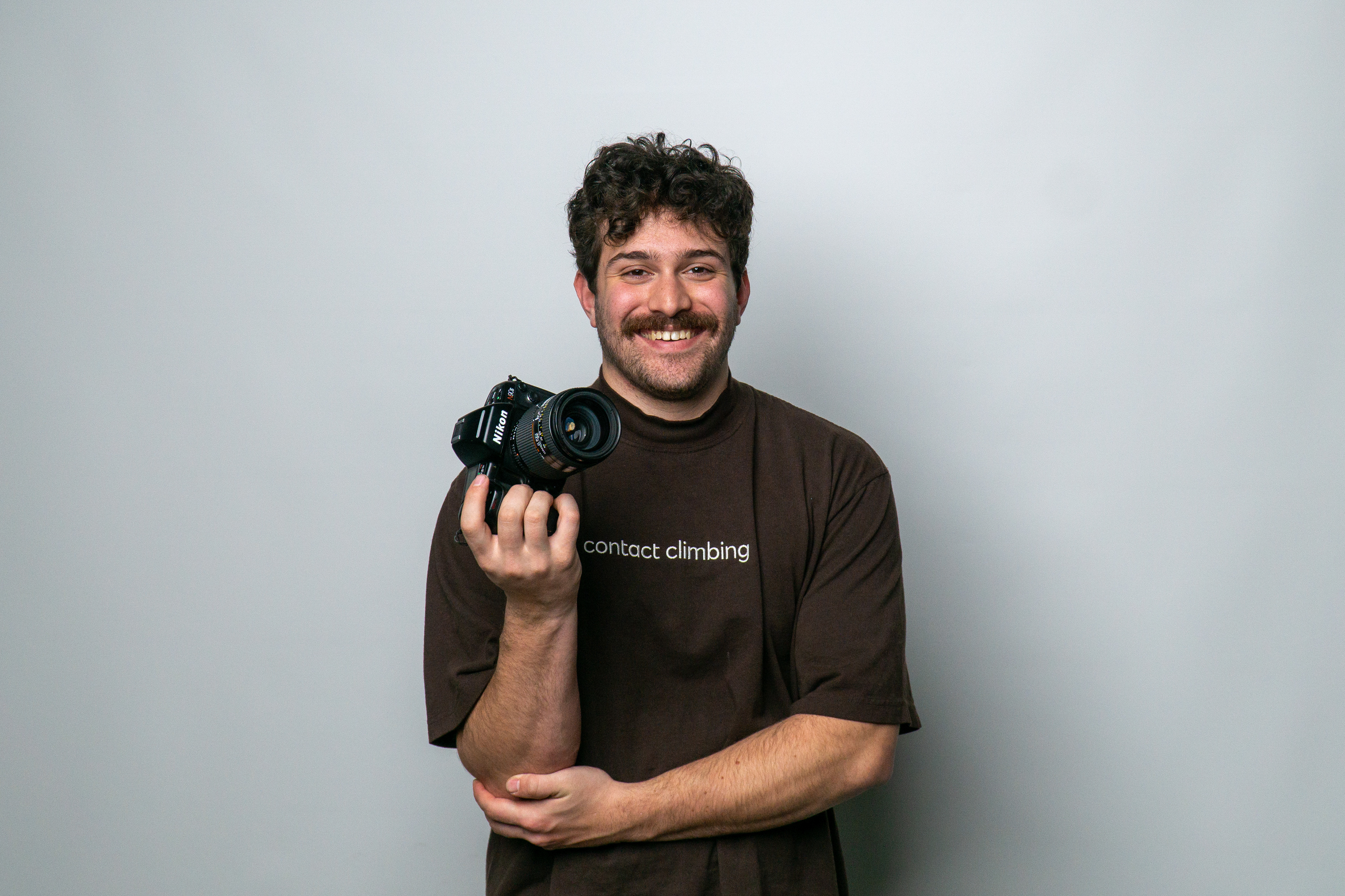 Photo of myself holding a film camera with a white studio backdrop.