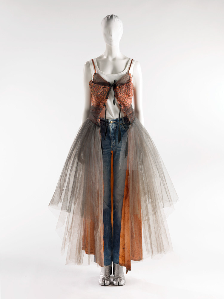 Martin Margiela (né en 1957). Robe du soir, marcel, jean et paire de tabis en cuir argenté. Personnalité représentée. Tulle artificiel gris rebordé de rubans de pongé rouille dessinant des maillons et tulle gris poussière. Tulle noir. Jersey à côtes de coton blanc. Cuir argenté. Printemps-été 1991. Galliera, musée de la Mode de la Ville de Paris. © Julien vidal / Roger-Viollet