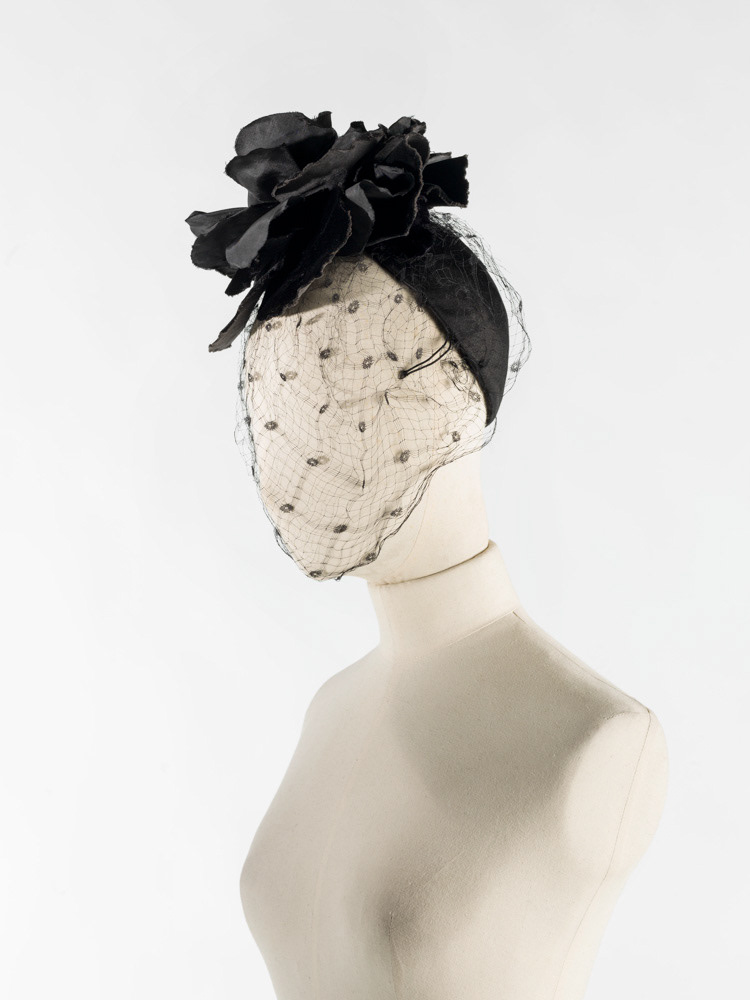 Cristobal Balenciaga (1895-1972). Calotte. Calotte de satin noir, montée sur sparterie, 2 pattes laitonnées, décor en velours et taffetas noir, voilette noire. 1960. Galliera, musée de la Mode de la Ville de Paris. © Julien vidal / Roger-Viollet