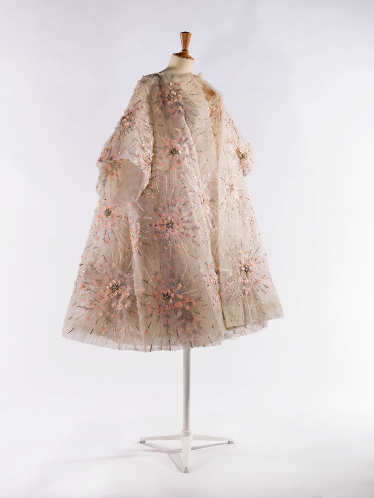 Garde-robe de Dalida. Balmain. Ensemble manteau et robe. Ensemble (habillement). Manteau : tulle blanc, broderie de soie blanche, soie rose et laminette argent au point lancé rehaussée de perles métallisées argent et de strass montés à griffes, application de pétales en toile de coton de différentes nuances de roses. 1961. Galliera, musée de la Mode de la Ville de Paris. © Julien vidal / Roger-Viollet