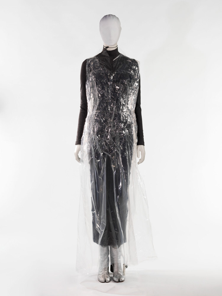 Martin Margiela (né en 1957). Robe flottante moulée sur un corps XXXL, tee-shirt et jupe moulants à coutures tirées et paire de tabis en cuir argent. Polyuréthanne transparent imprimé mis en forme par du scotch transparent, flanelle biélastique coton et élasthanne à coutures tirées. Automne-hiver 1992. Galliera, musée de la Mode de la Ville de Paris. © Julien vidal / Roger-Viollet