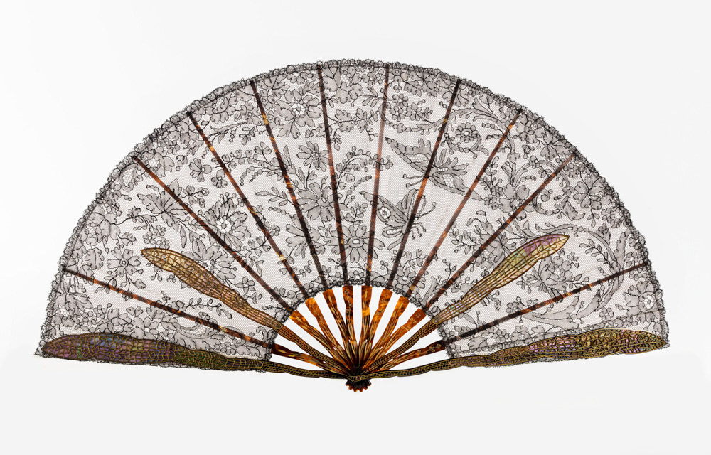 Eventail, composé de 12 brins. Feuille en dentelle de Chantilly noire à motif sur fond de gaze rose, monture en écaille jaspée, gravée et dorée, panache, contre-panache et 2 brins en forme d'aile de papillon en écaille repercée et appliquée sur un fond d'alliotis à reflets rose et vert, rivure en pierre rouge. 1895-1905. Galliera, musée de la Mode de la Ville de Paris. © Julien vidal / Roger-Viollet