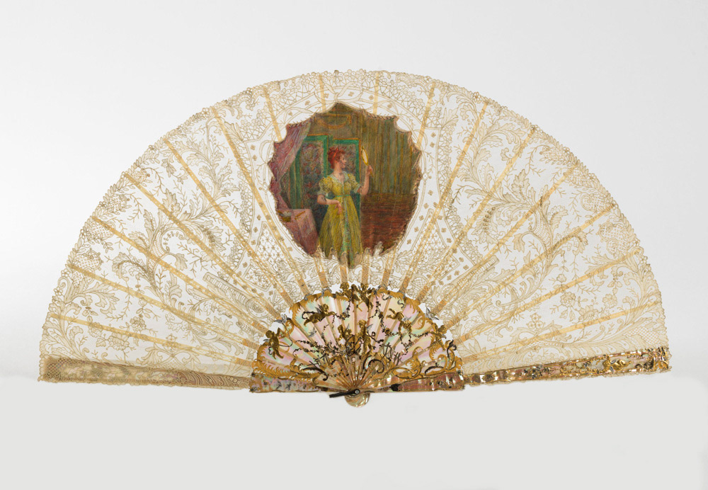 Eventail. Dentelle au point de gaze, cartouche en canepin peint à la gouache, nacre repercée, gravée, sculptée, dorée et argentée, métal. Vers 1892. Galliera, musée de la Mode de la Ville de Paris. © Julien vidal / Roger-Viollet