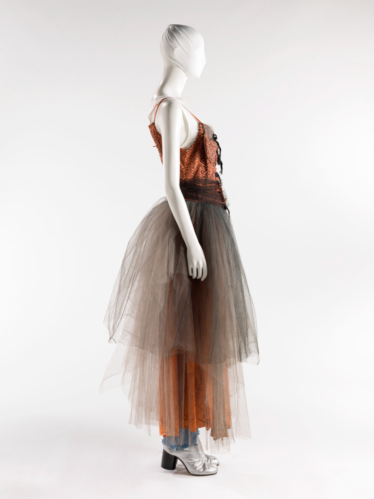Martin Margiela (né en 1957). Robe du soir, marcel, jean et paire de tabis en cuir argenté. Personnalité représentée. Tulle artificiel gris rebordé de rubans de pongé rouille dessinant des maillons et tulle gris poussière. Tulle noir. Jersey à côtes de coton blanc. Cuir argenté. Printemps-été 1991. Galliera, musée de la Mode de la Ville de Paris. © Julien vidal / Roger-Viollet