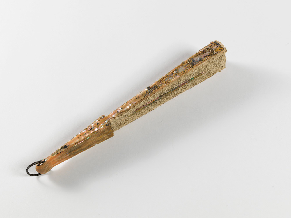 Eventail plié. Dentelle au point de gaze, cartouche en canepin peint à la gouache, nacre repercée, gravée, sculptée, dorée et argentée, métal. Vers 1892. Galliera, musée de la Mode de la Ville de Paris. © Julien vidal / Roger-Viollet