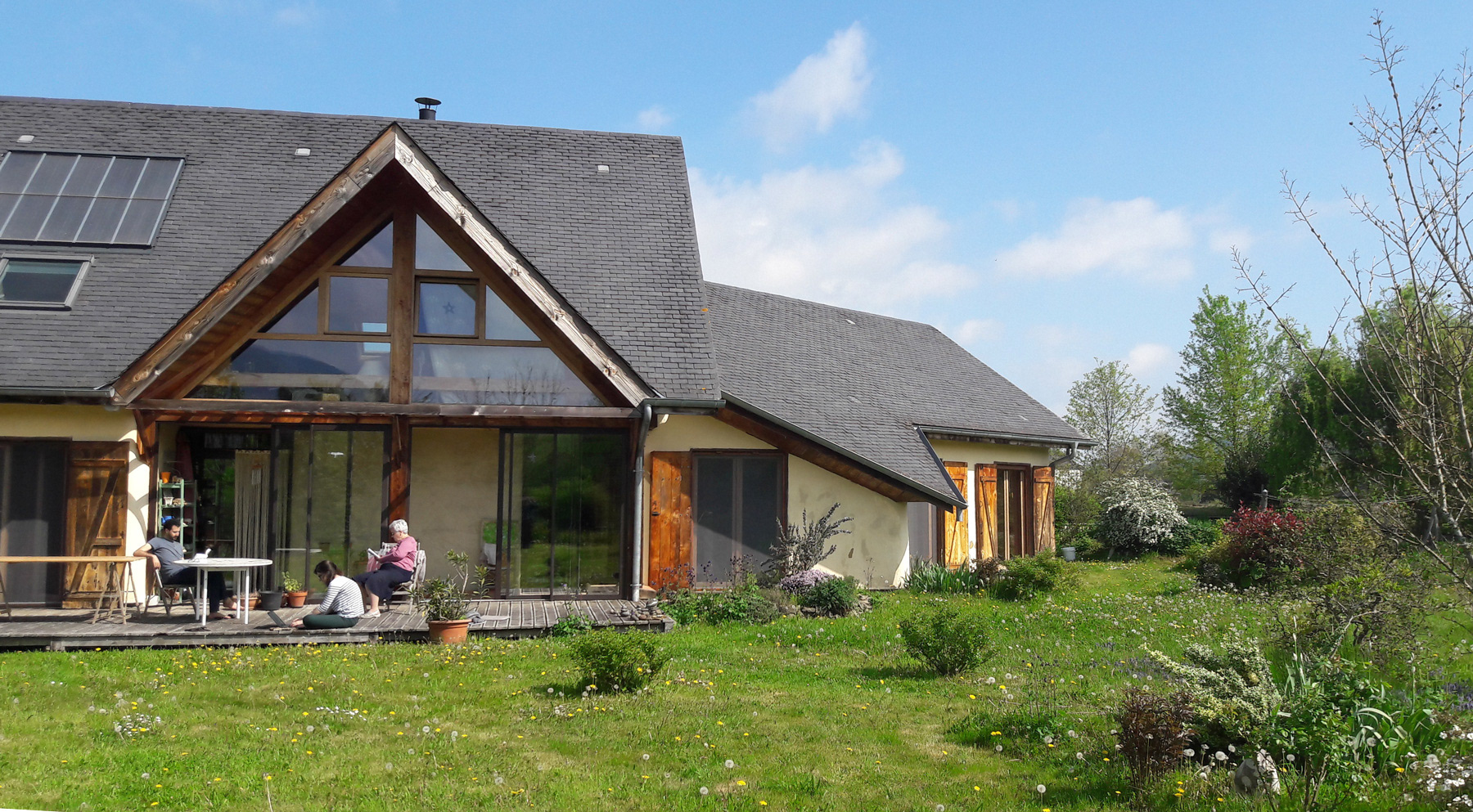 Maison en écologique autoconstruite en bois, terre, paille, vue depuis le jardin ensoleillé