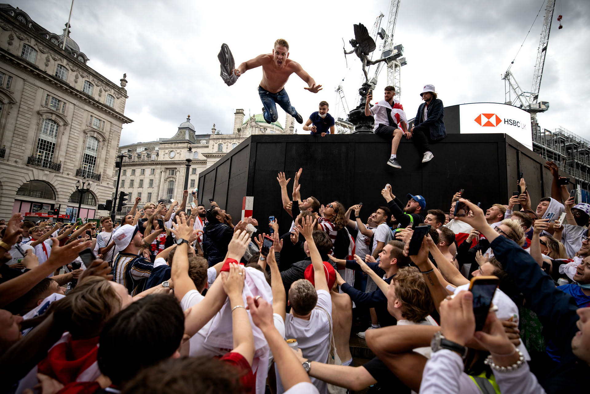 A man jumps from the Eros statue in Piccadilly Circus ahead of the UEFA EURO 2020 final