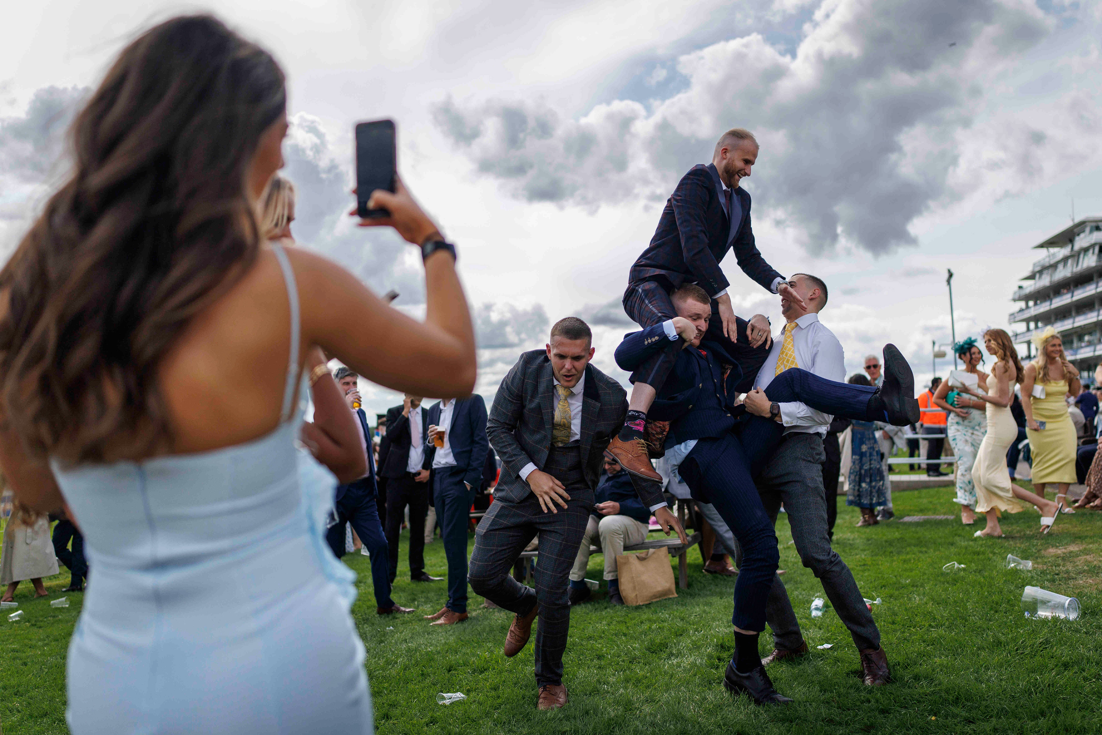Race-goers carry each other as they pose for a picture in between horse races during Ladies Day at the Epsom Derby