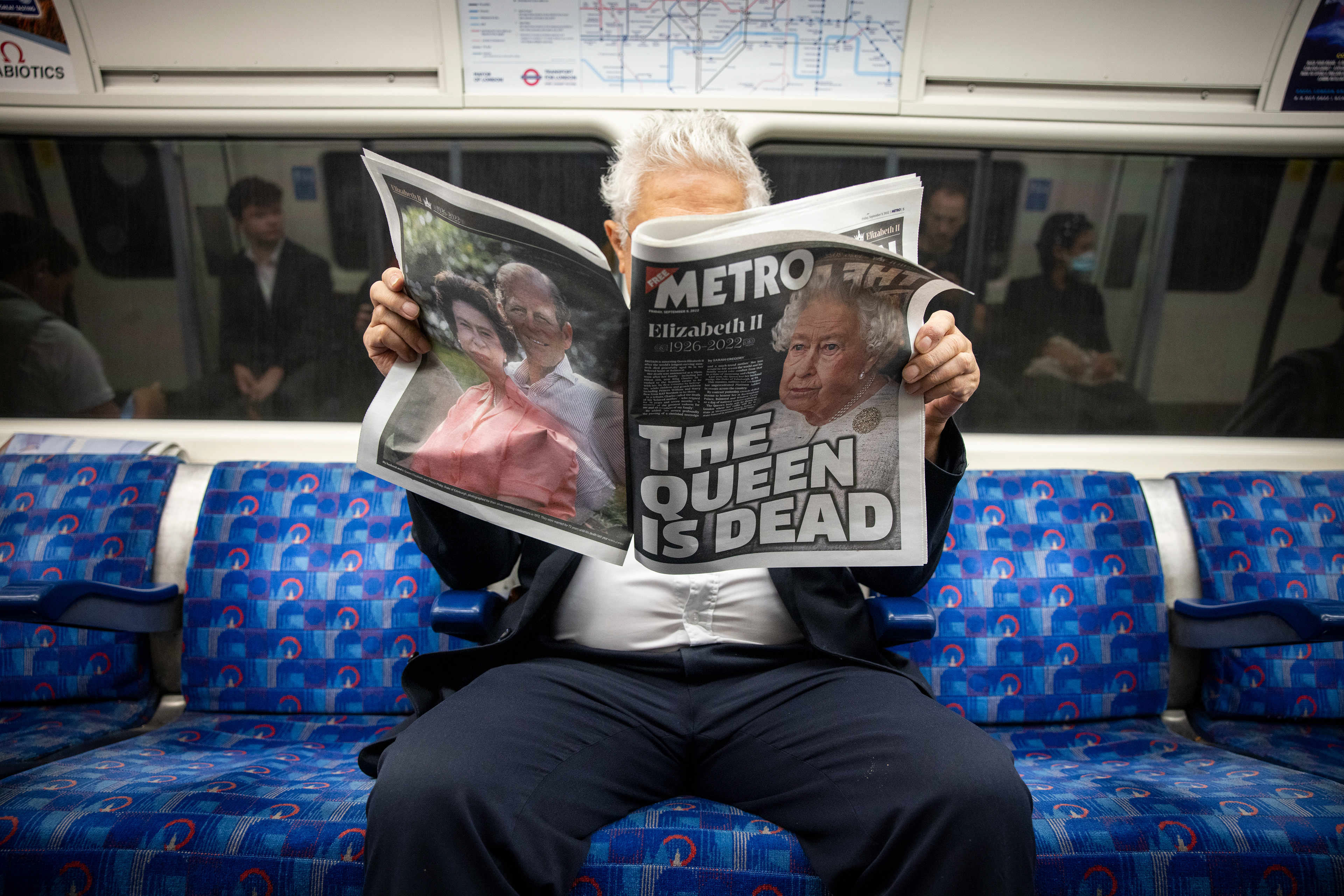 A commuter reads a newspaper reporting on the passing of Queen Elizabeth II