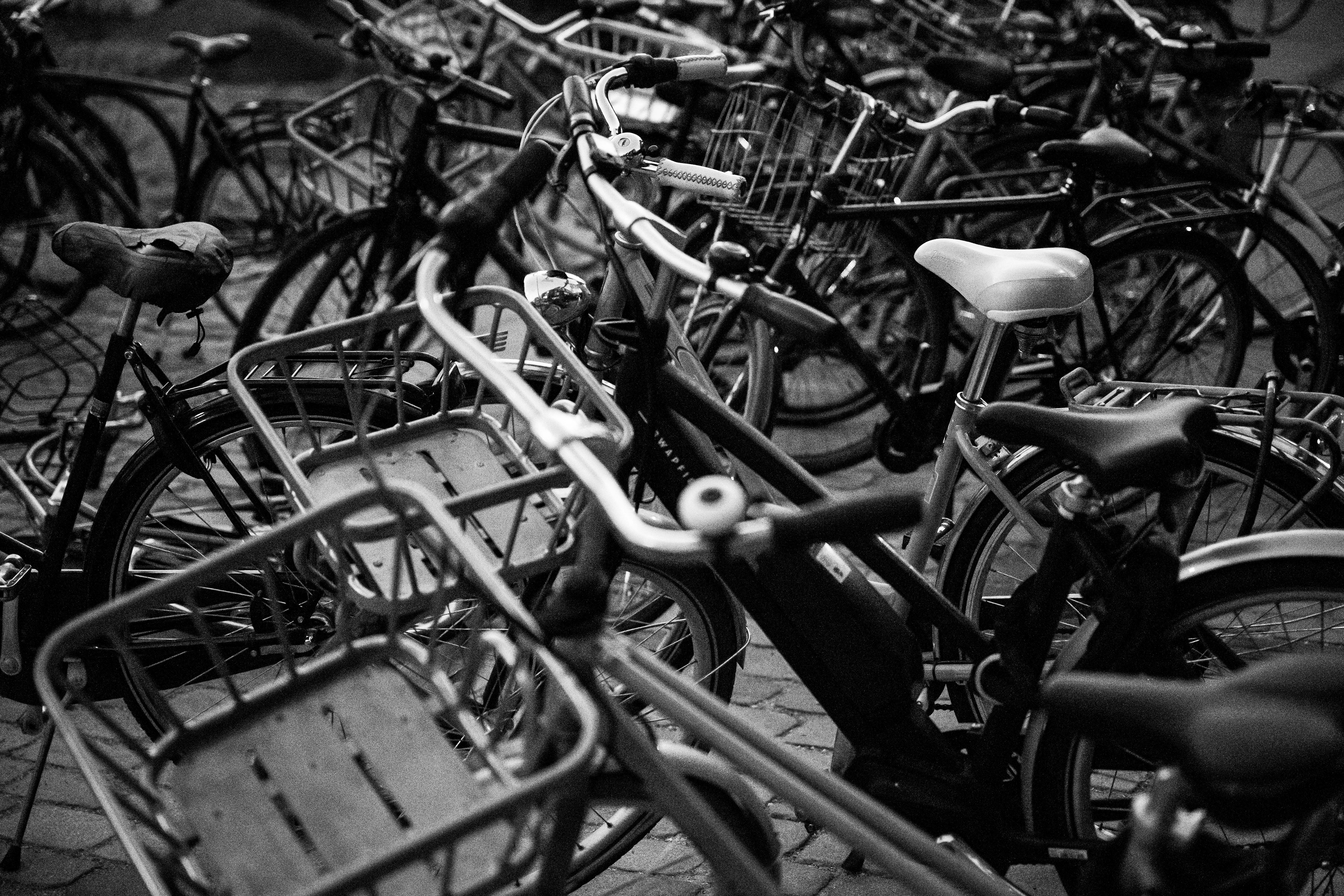 Trame a pedali: catasta di biciclette parcheggiate con cestini, manubri e selle che si sovrappongono, bianco e nero, Copenaghen, fotografia di Fabio Alimonti