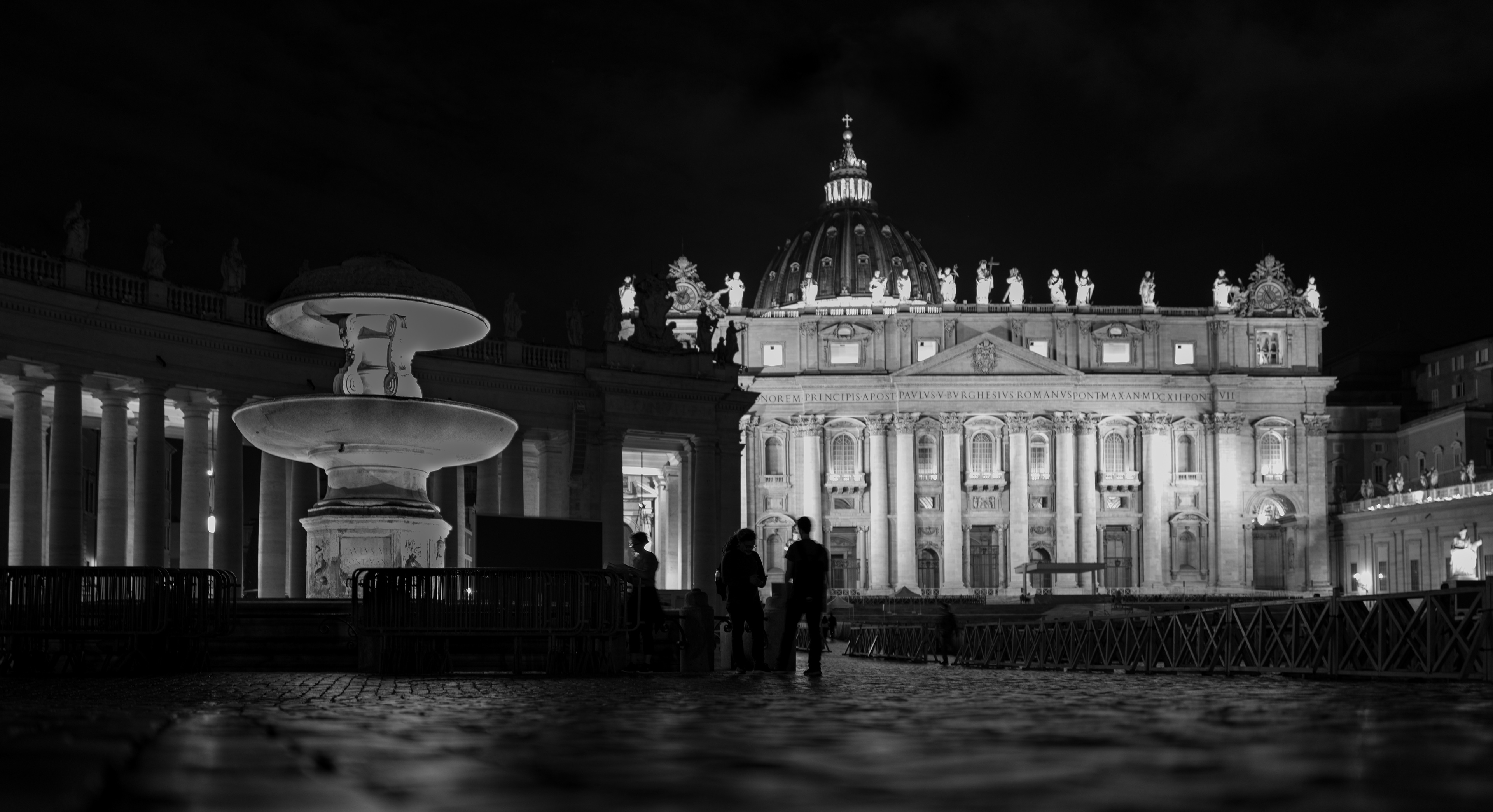 Gli ultimi – due figure in silhouette davanti alla Basilica di San Pietro illuminata di notte, fotografia in bianco e nero di Fabio Alimonti